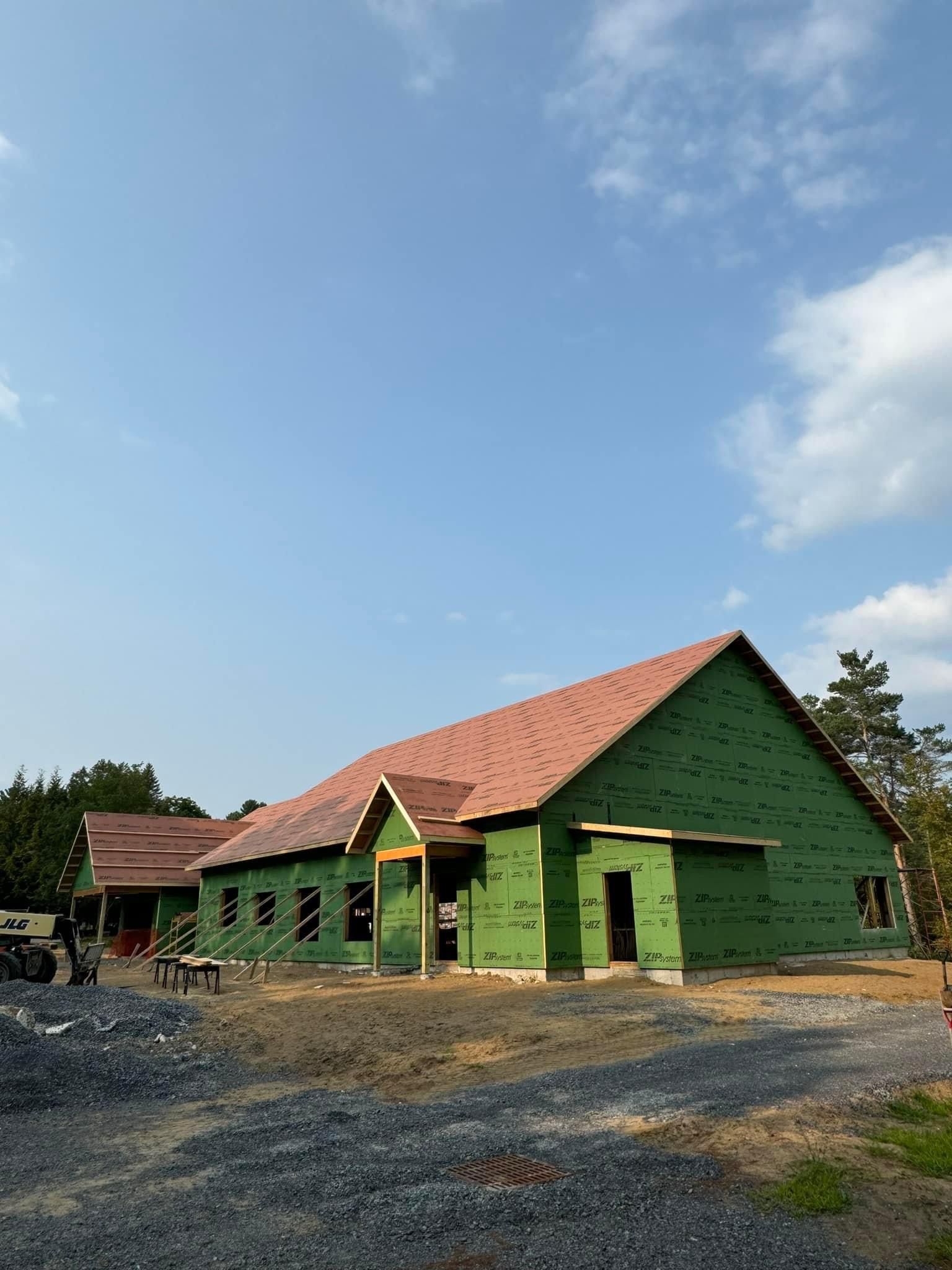 A large green house with a red roof is being built.