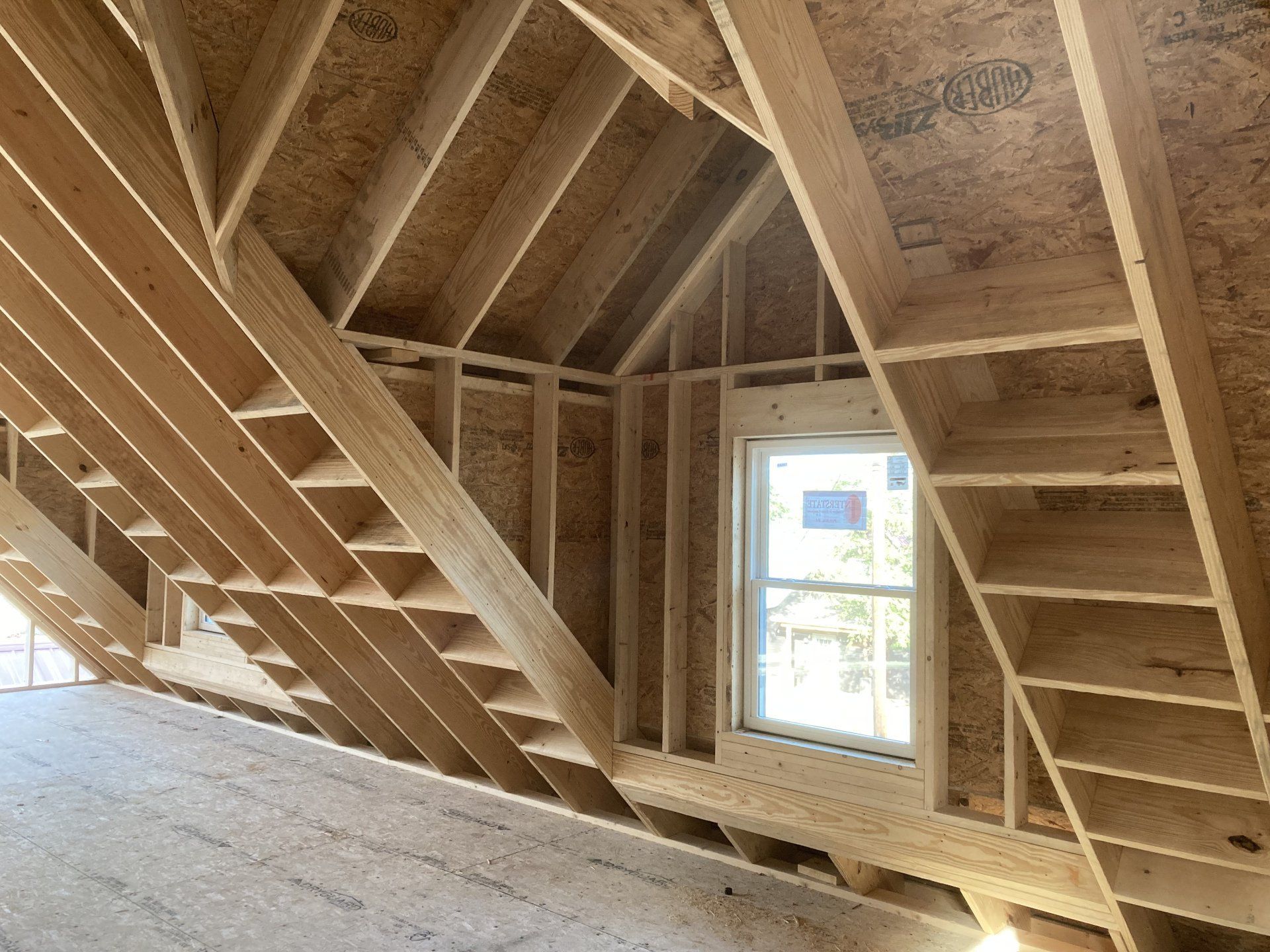 There is a window in the attic of a house under construction.