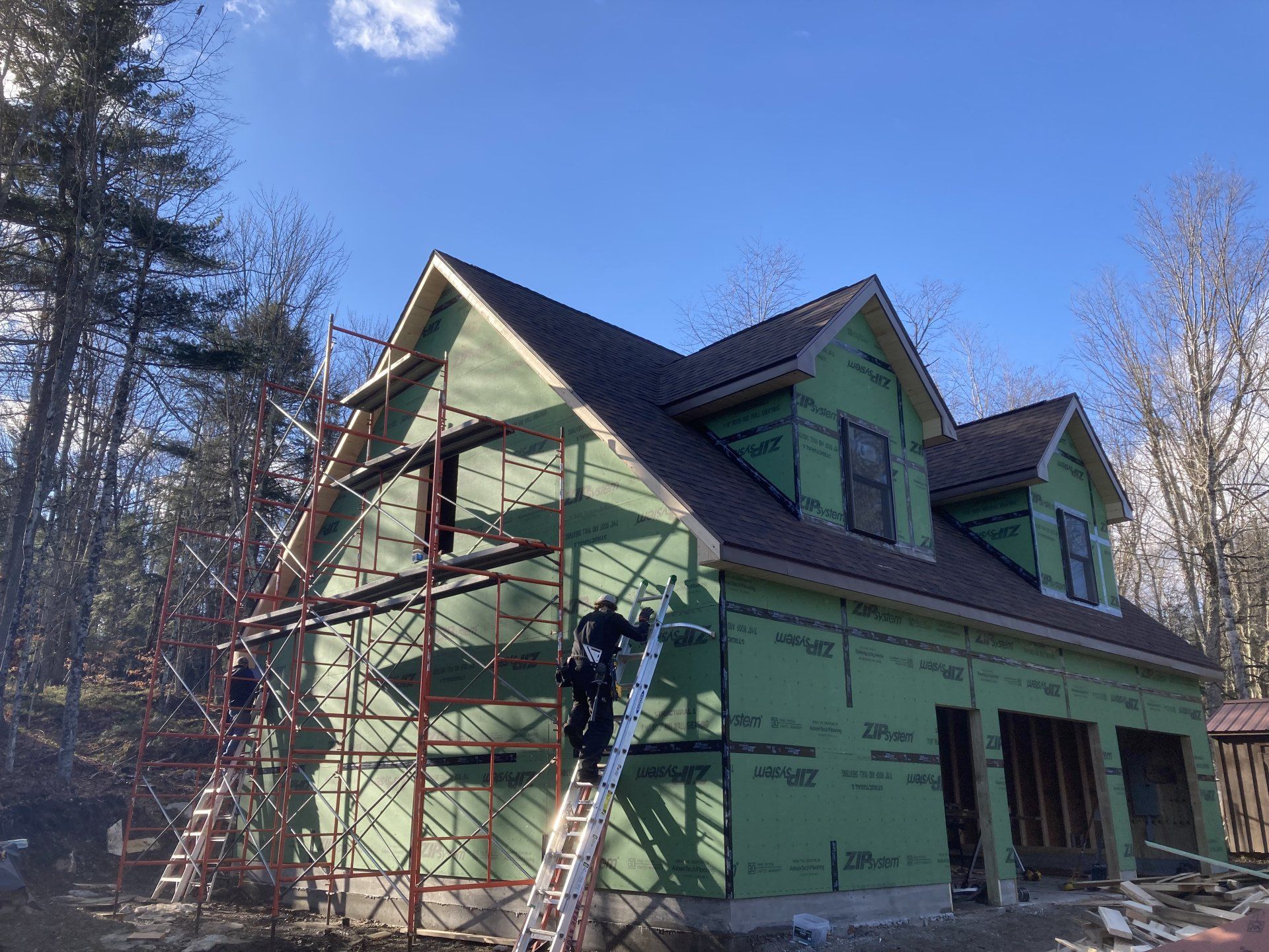 A house is being built with green siding and scaffolding.