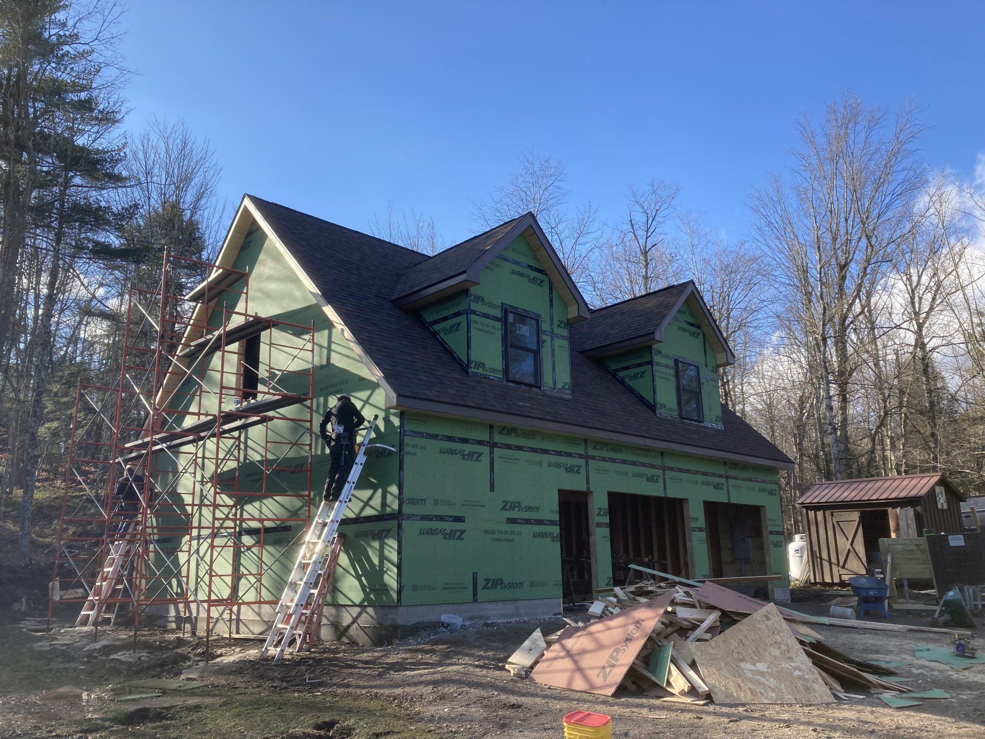 A house is being built with green siding and a roof.