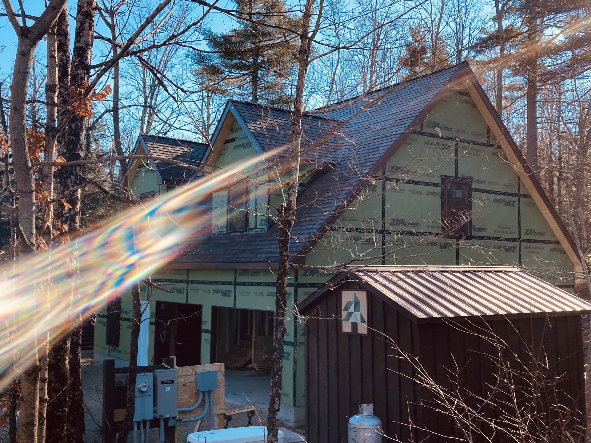 A house is being built in the woods and the sun is shining through the trees