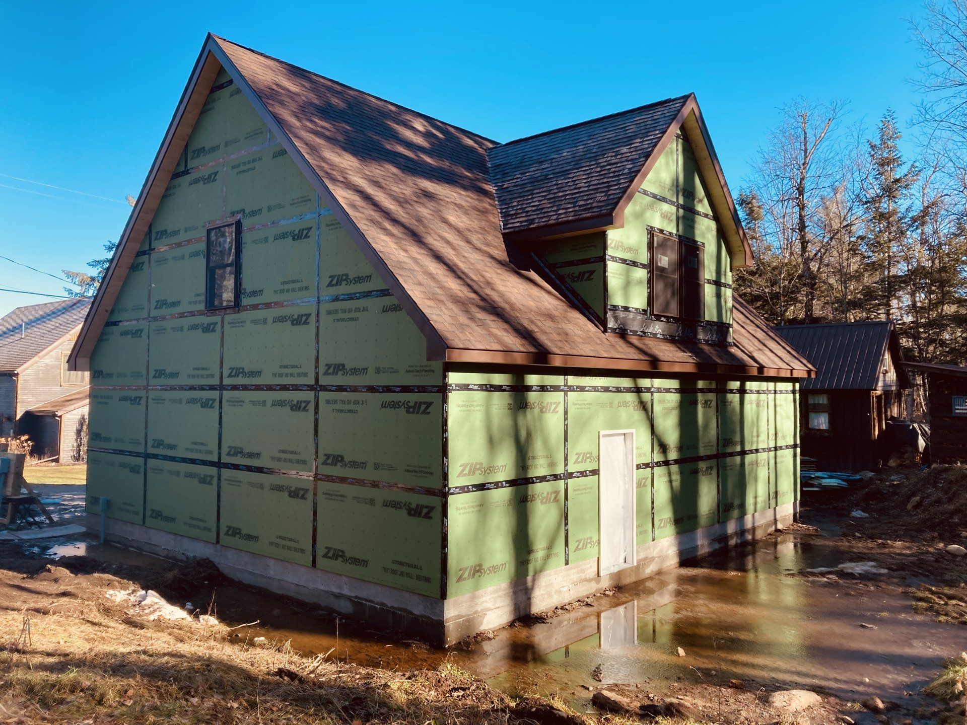 A house is being built with green siding and a brown roof.