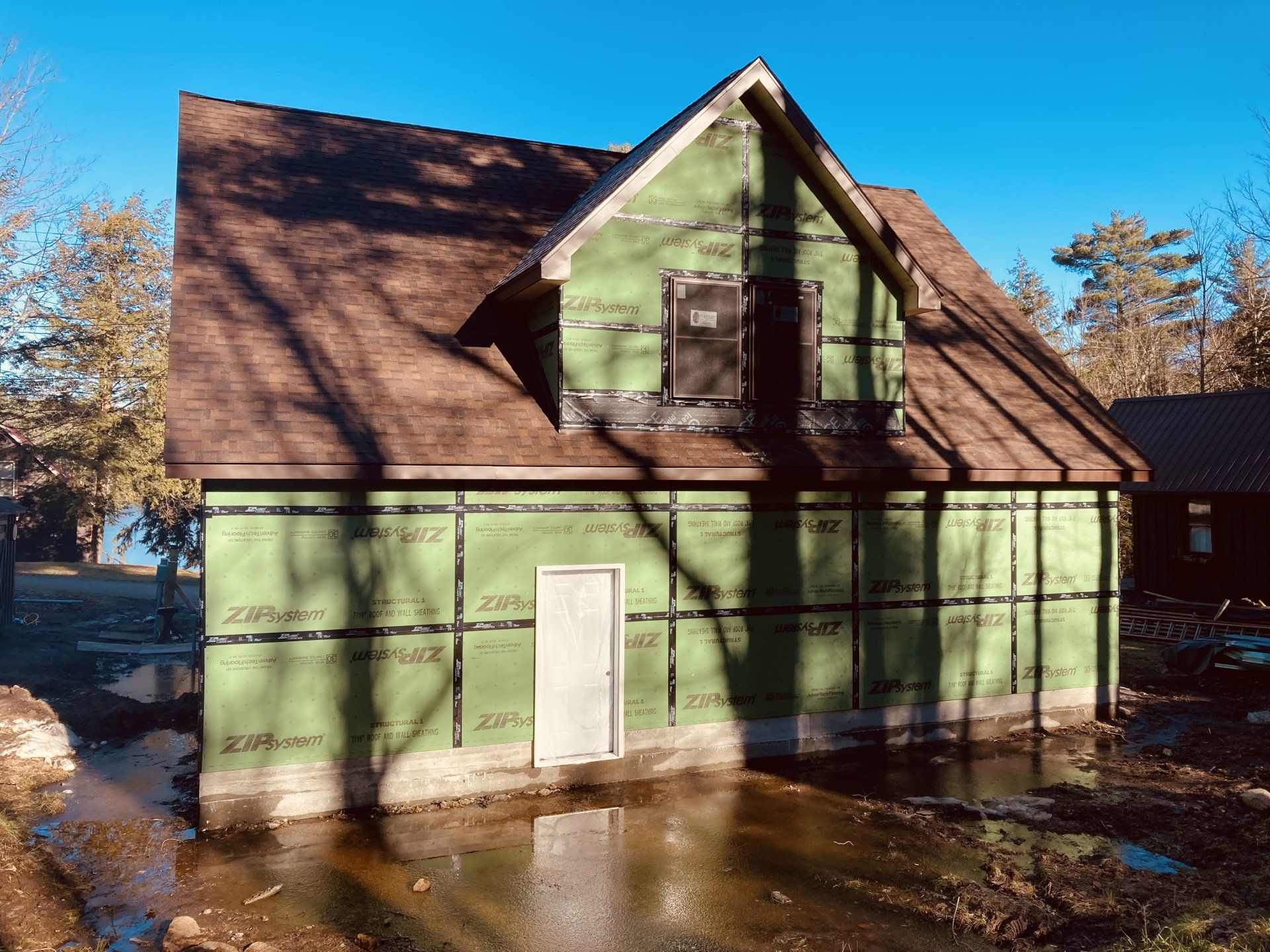 A house is being built with green siding and a brown roof.
