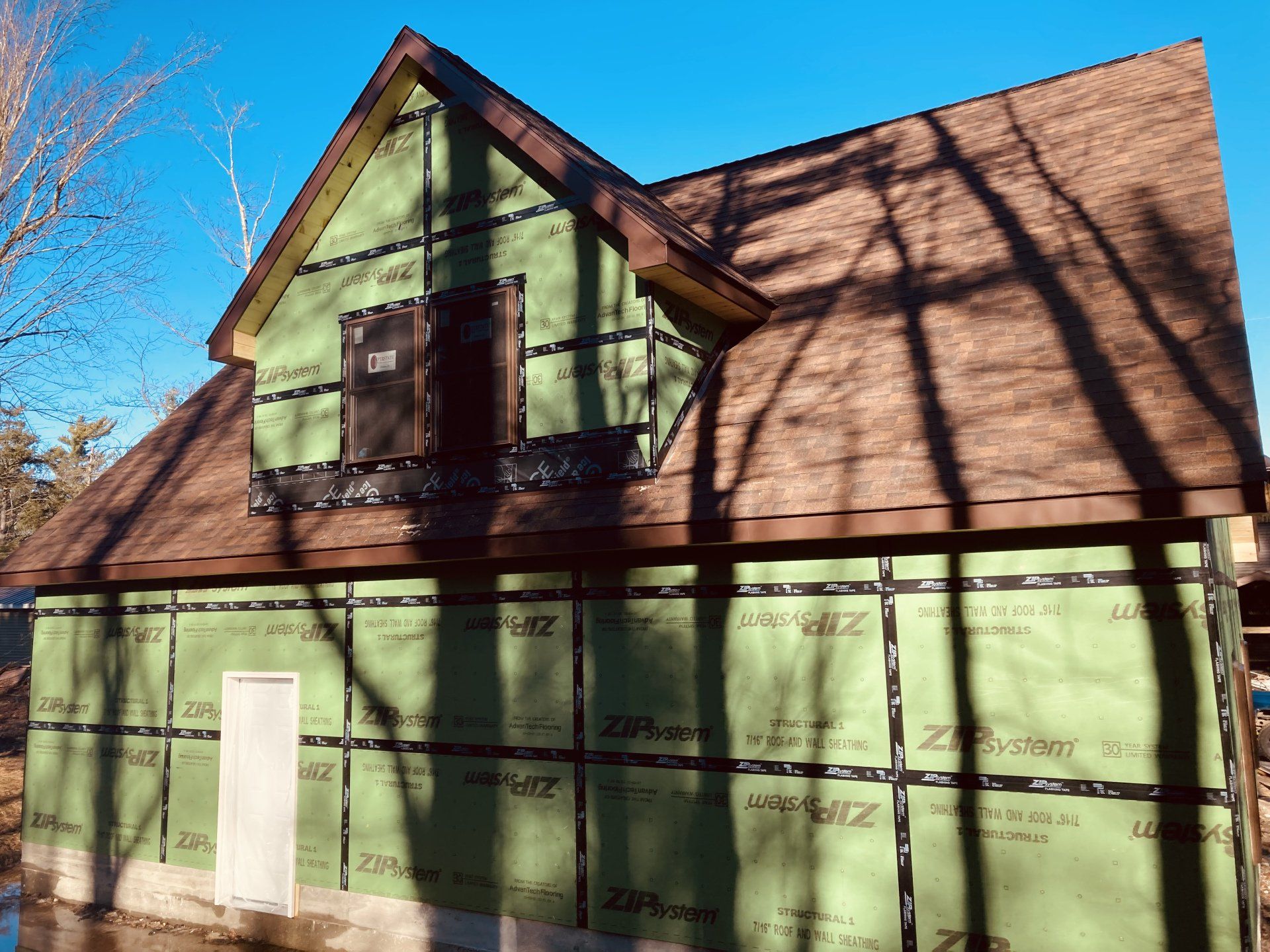 A house is being built with green siding and a brown roof