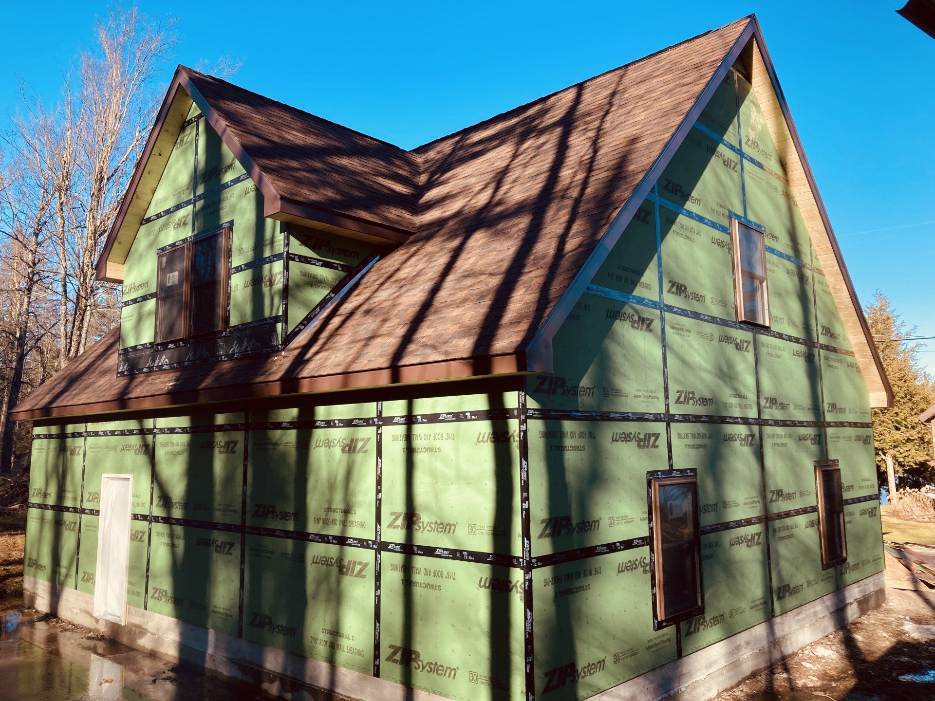 A house is being built with green siding and a brown roof.