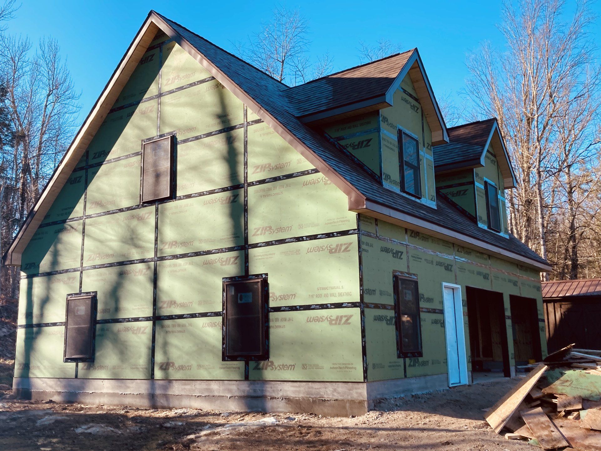 A house is being built with green siding and a roof.
