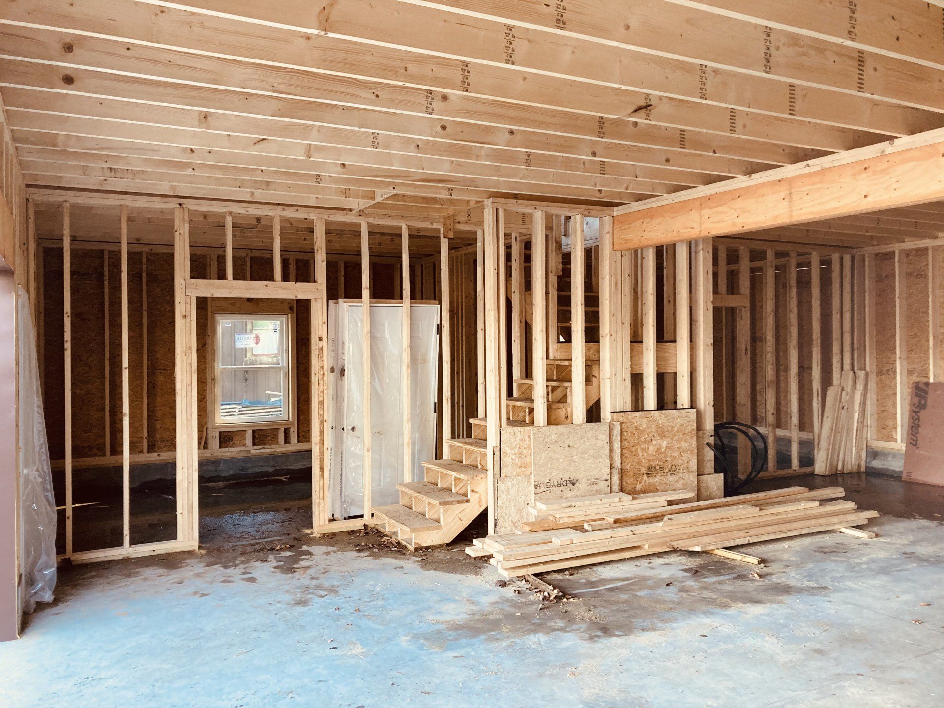 The inside of a house under construction with wooden beams and stairs.