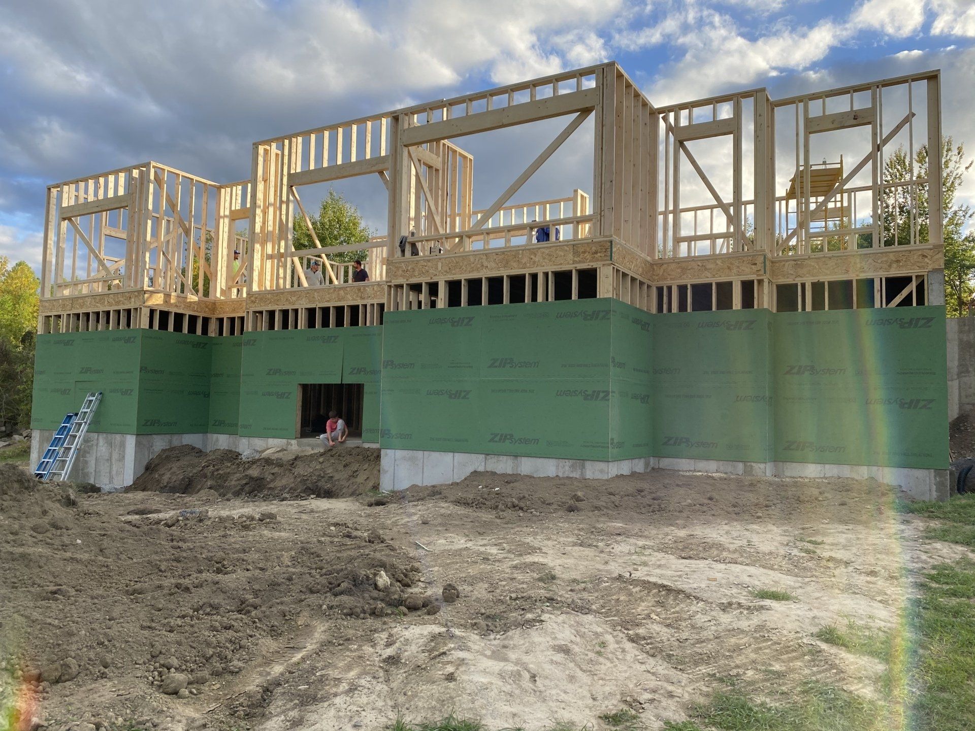 A large house is being built in the middle of a dirt field.