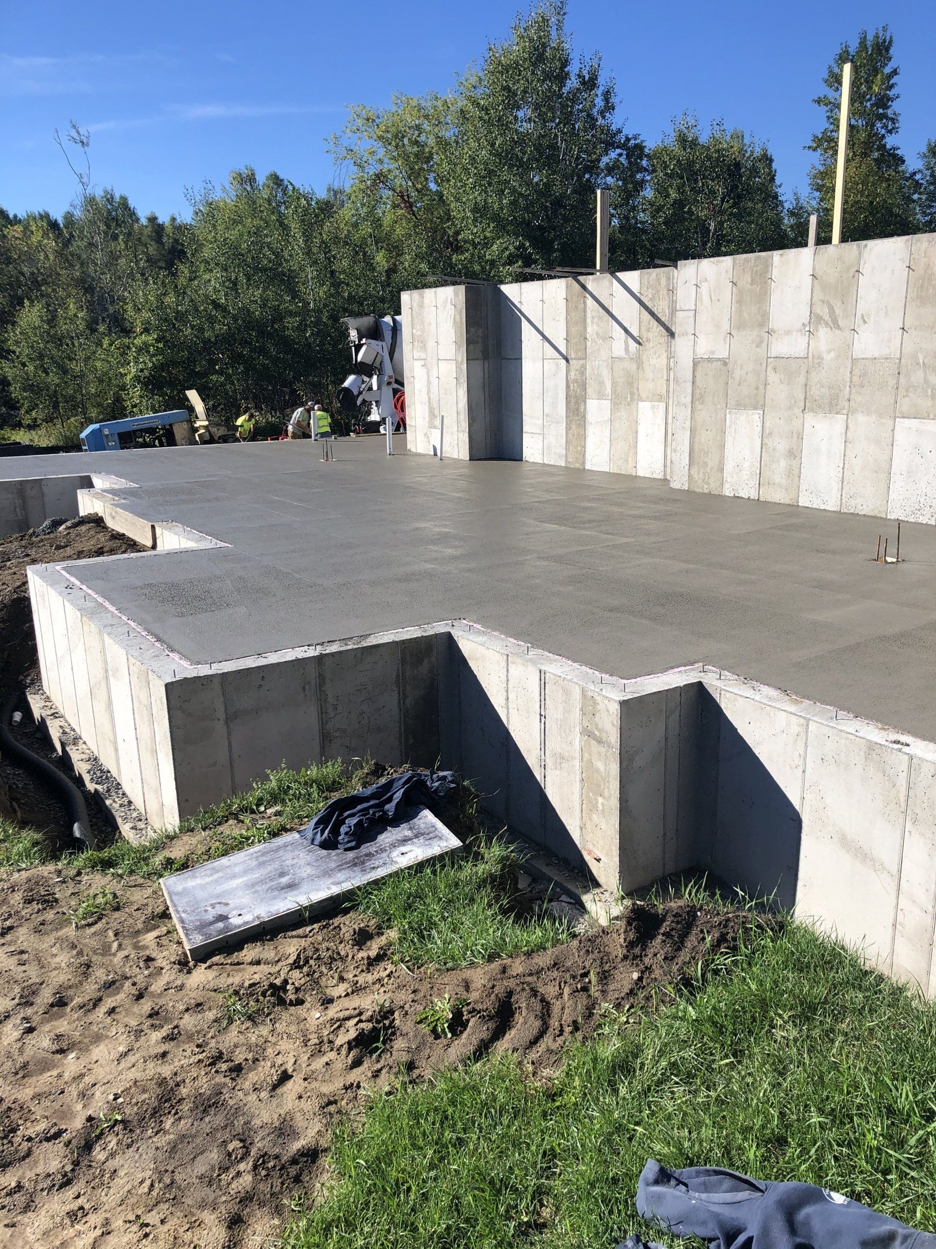 A concrete base for a house is being built in the grass.