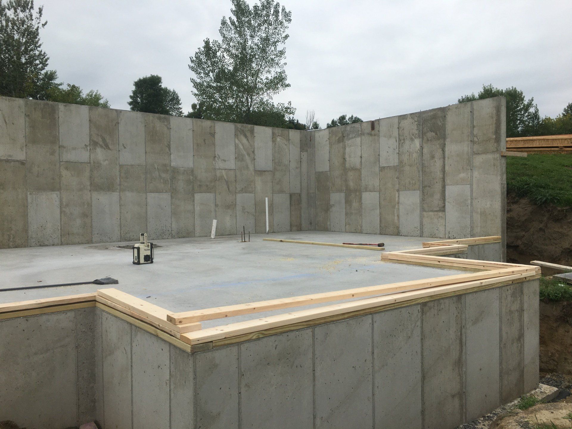 A large concrete wall is being built in the middle of a field.