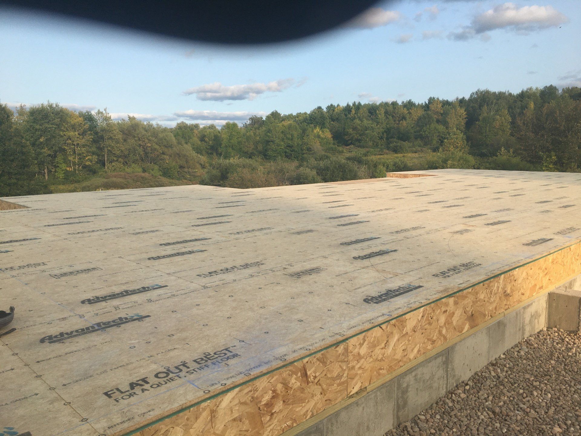 A roof with a lot of shingles on it and trees in the background.