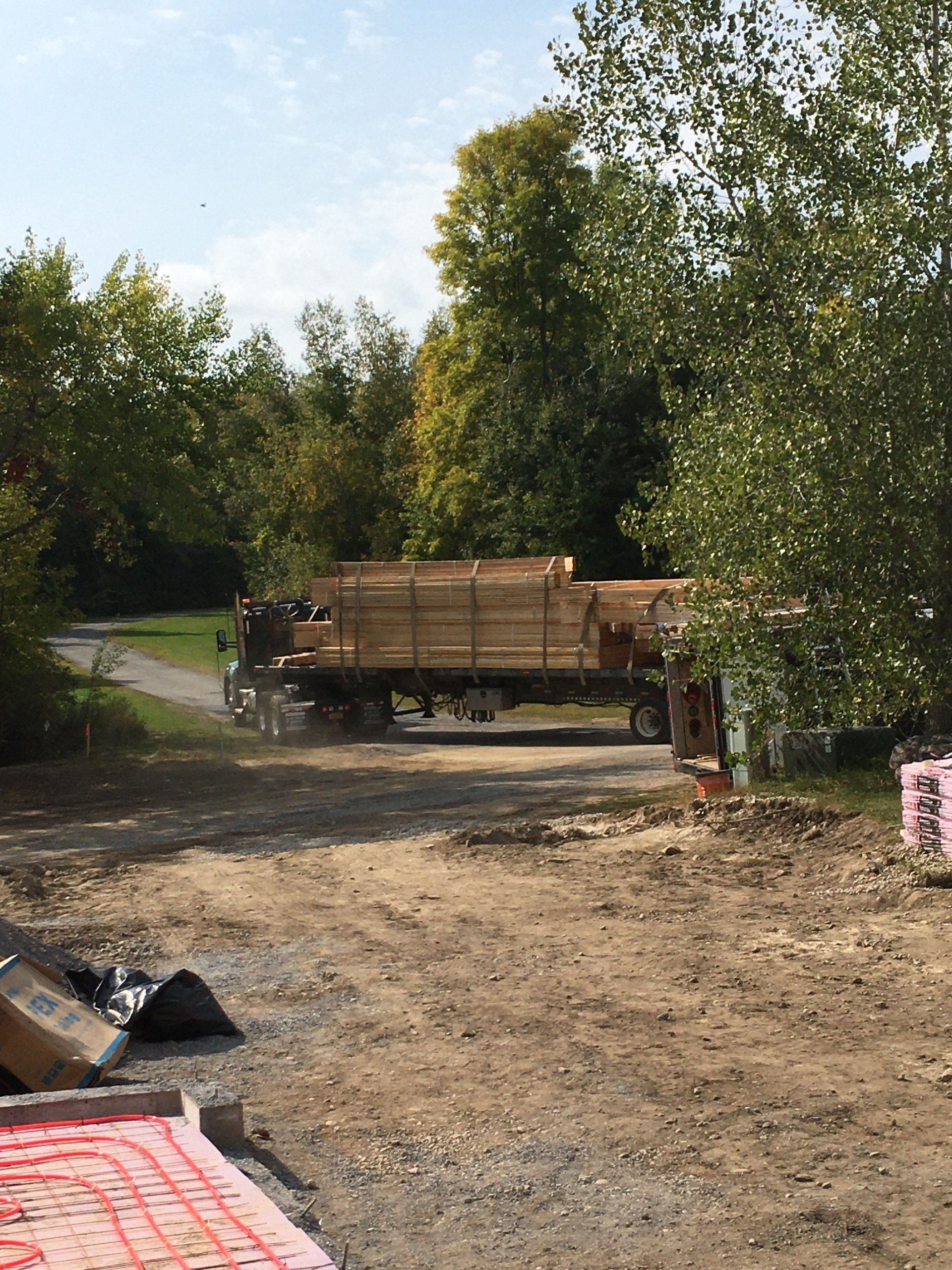 A large truck is driving down a dirt road.