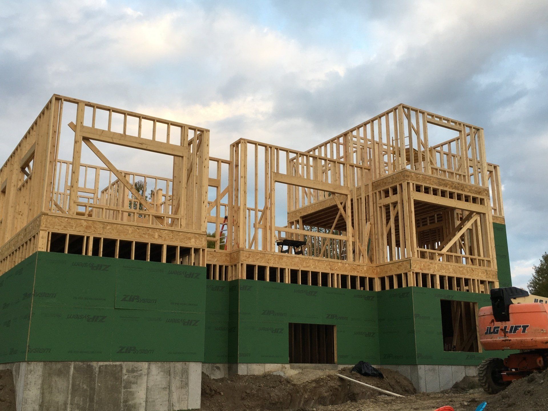 A large wooden house is being built on top of a dirt hill.