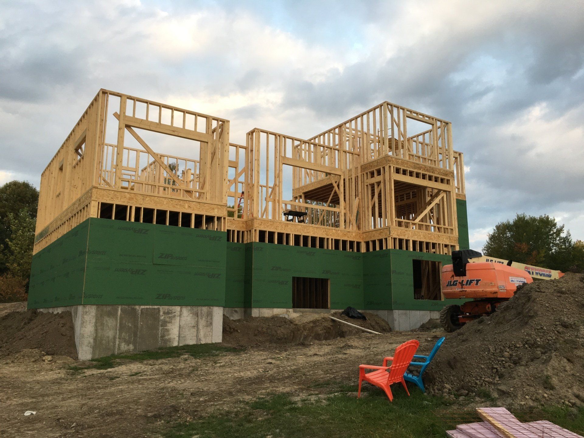 A large house is being built in the middle of a dirt field.