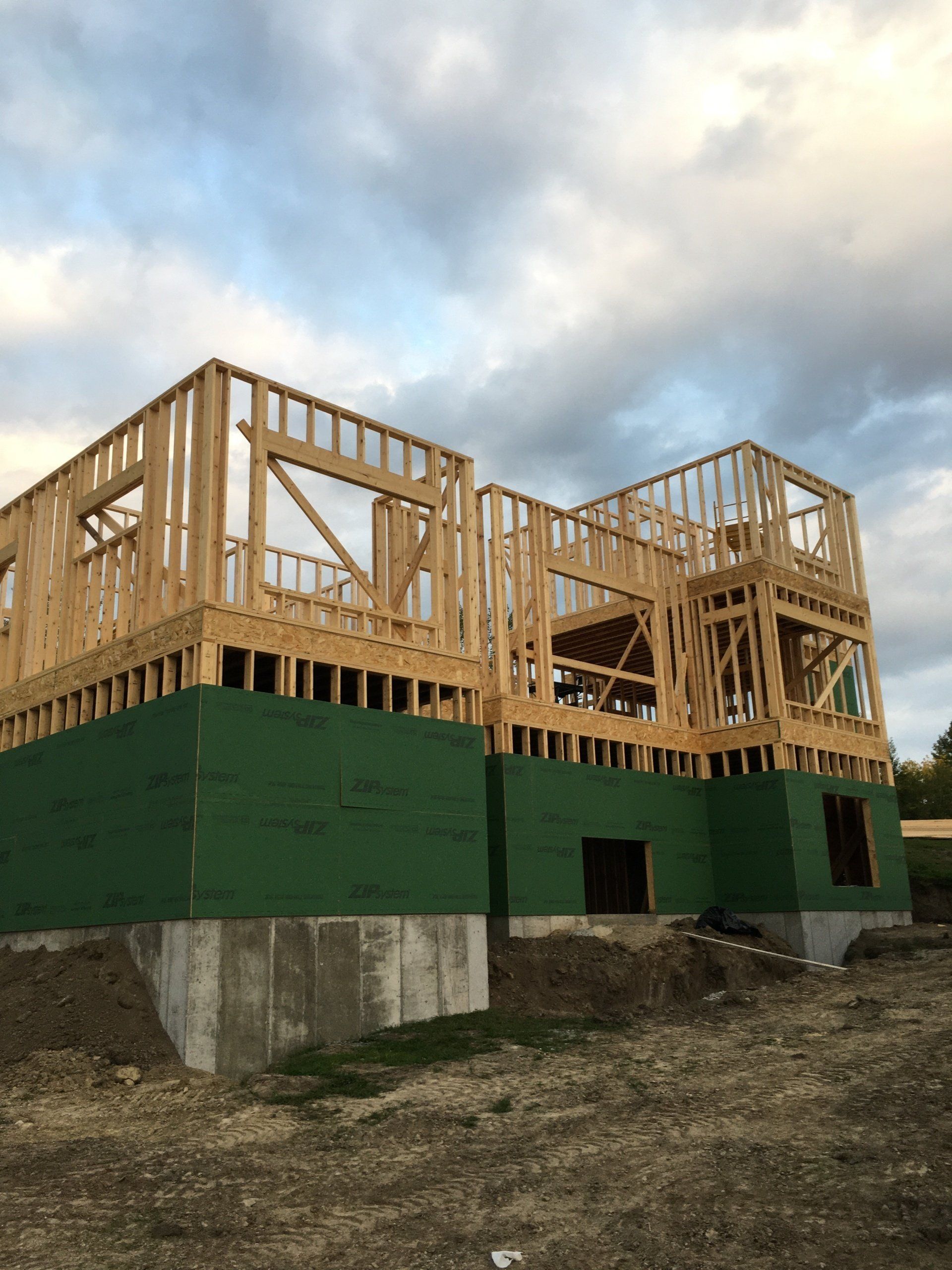 A large wooden house is being built in a field.