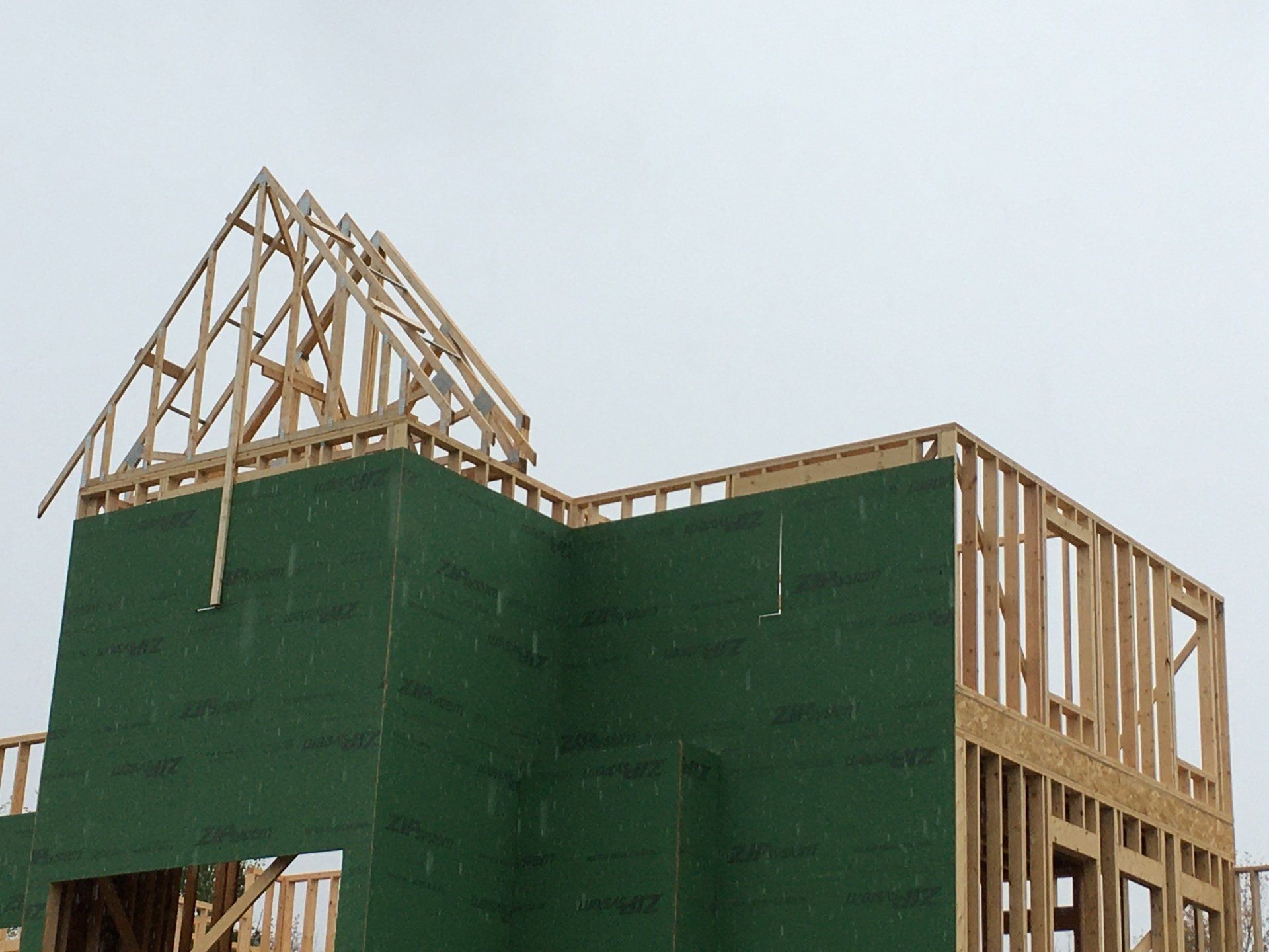 A house is being built with green walls and a wooden roof