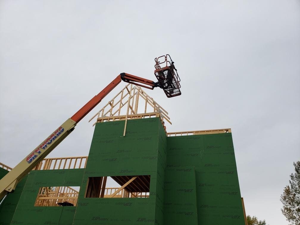 A crane is lifting a wooden structure on top of a building under construction.