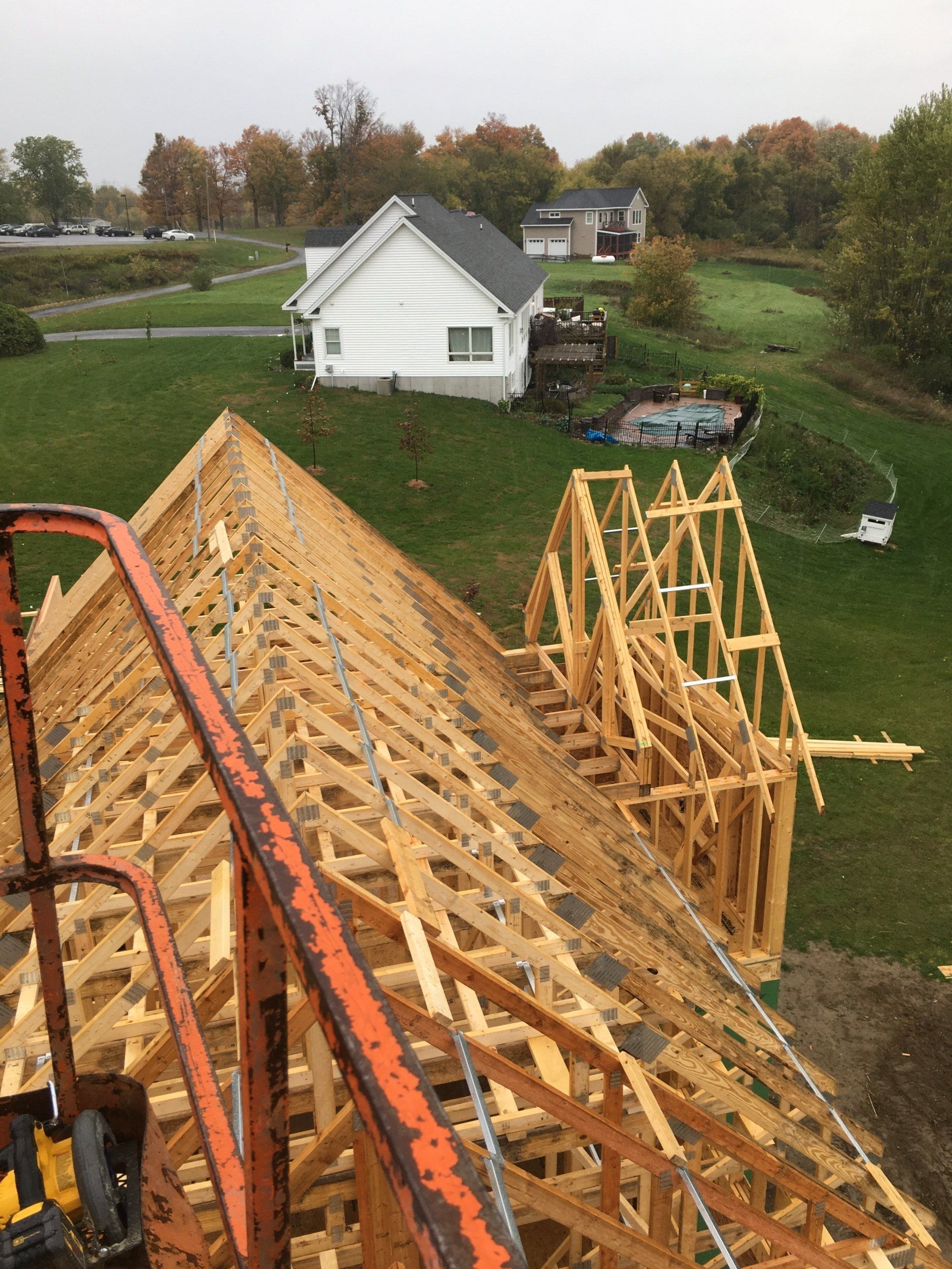 A large wooden structure is being built in a field with a house in the background.