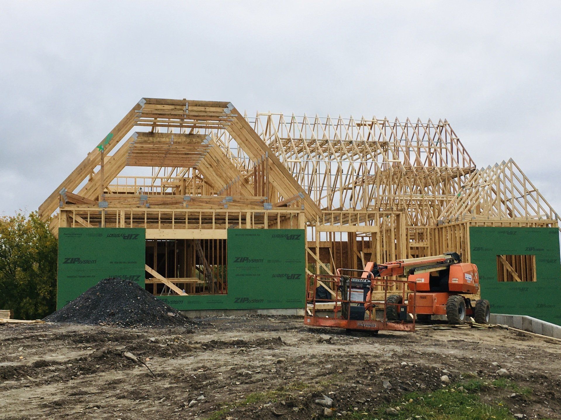 A large wooden house is being built in a dirt field.