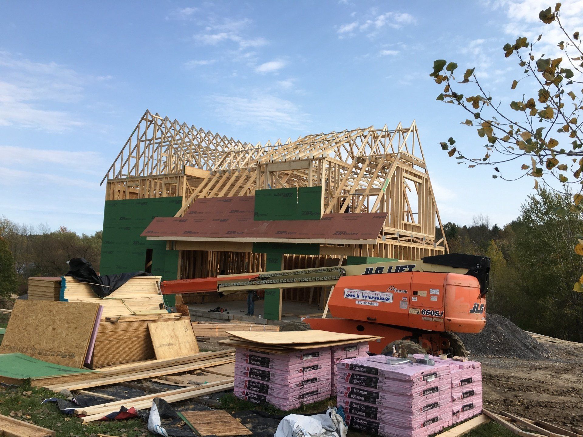 A house is being built with a jlg lift in the foreground.