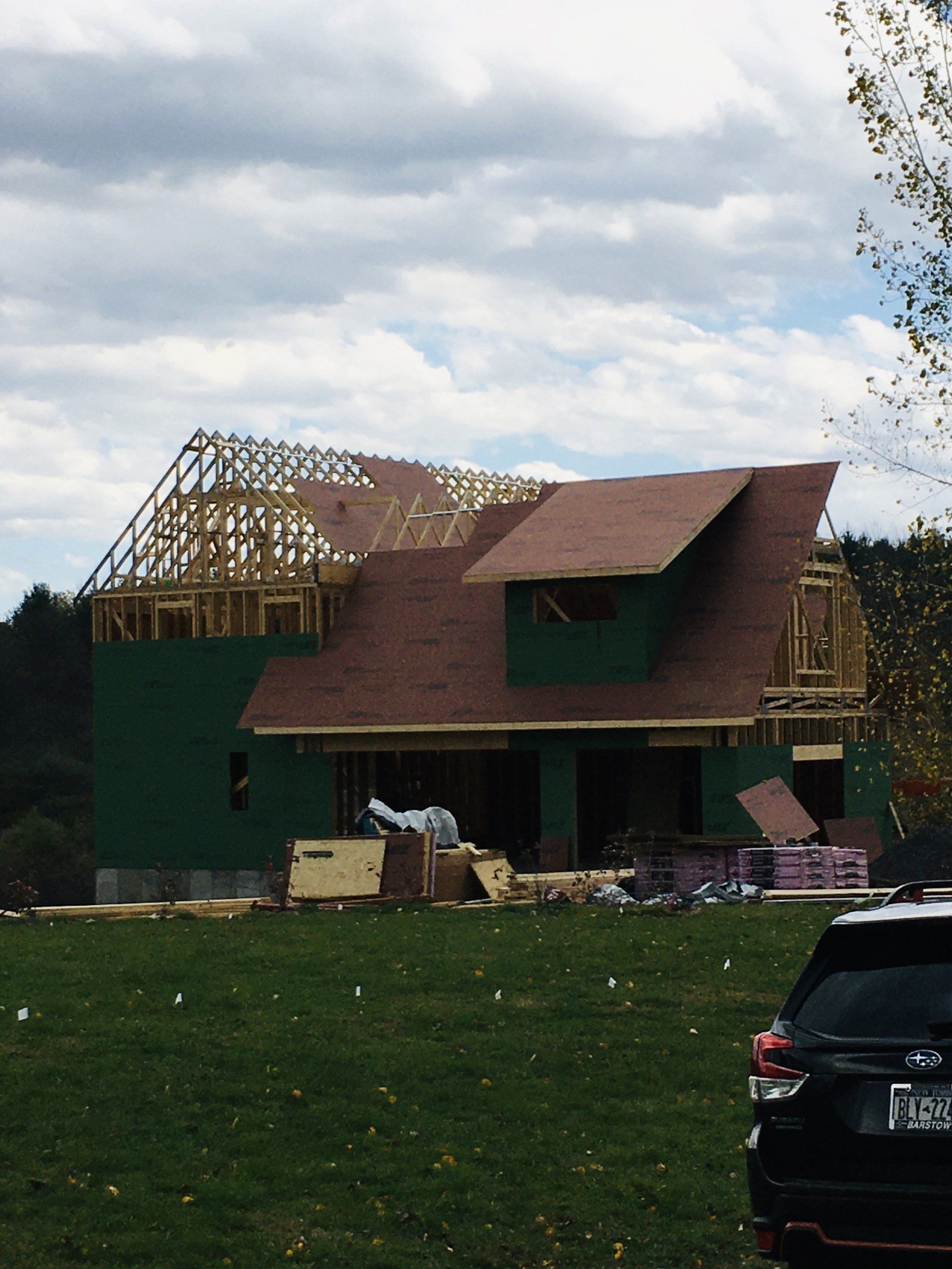 A car is parked in front of a house under construction