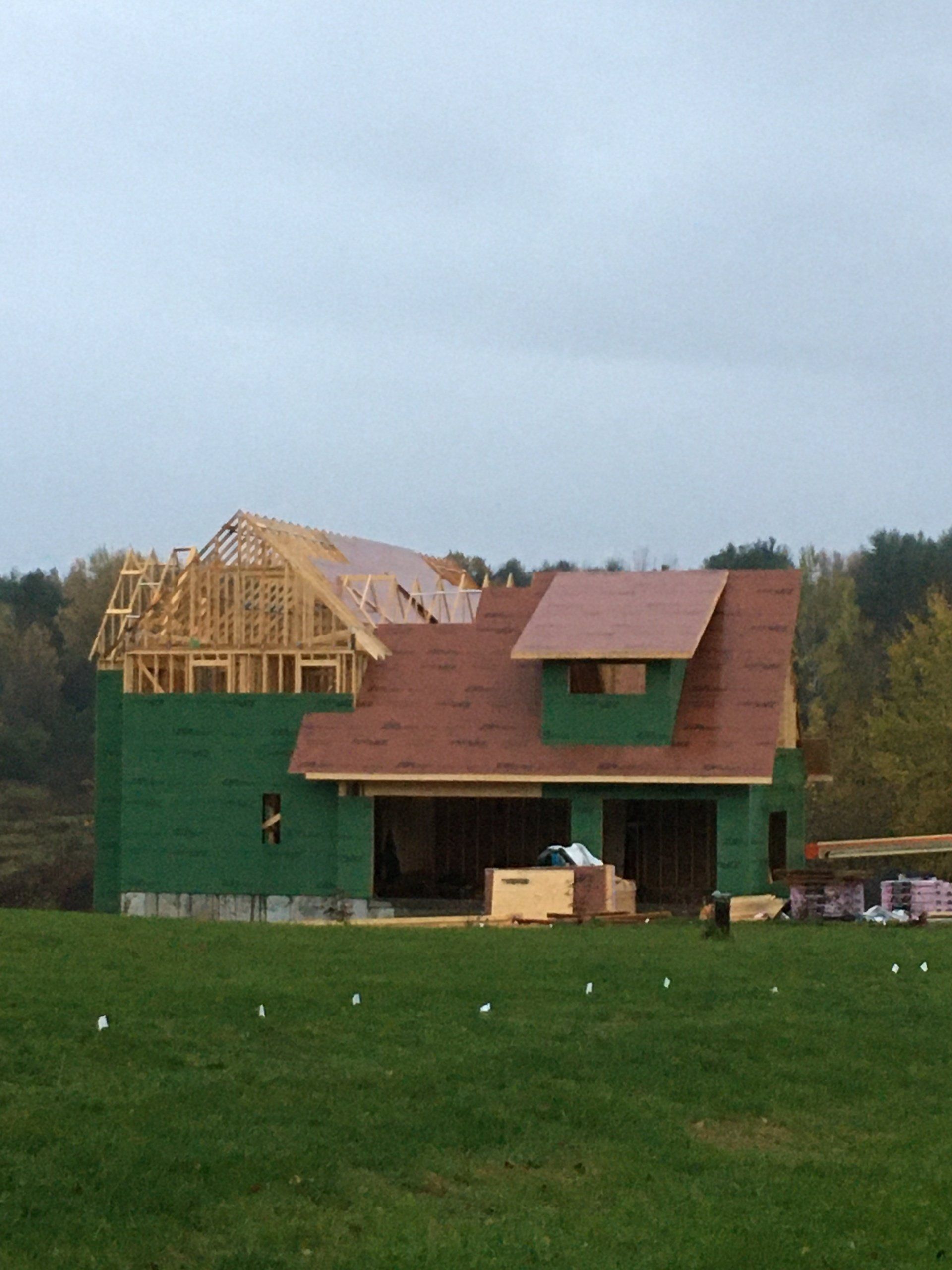 A house is being built in a grassy field.