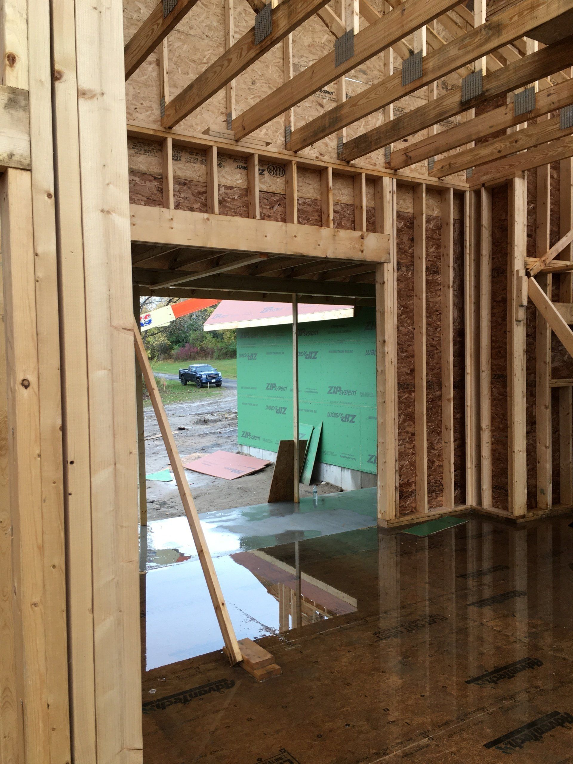 The inside of a house under construction with a puddle of water on the floor