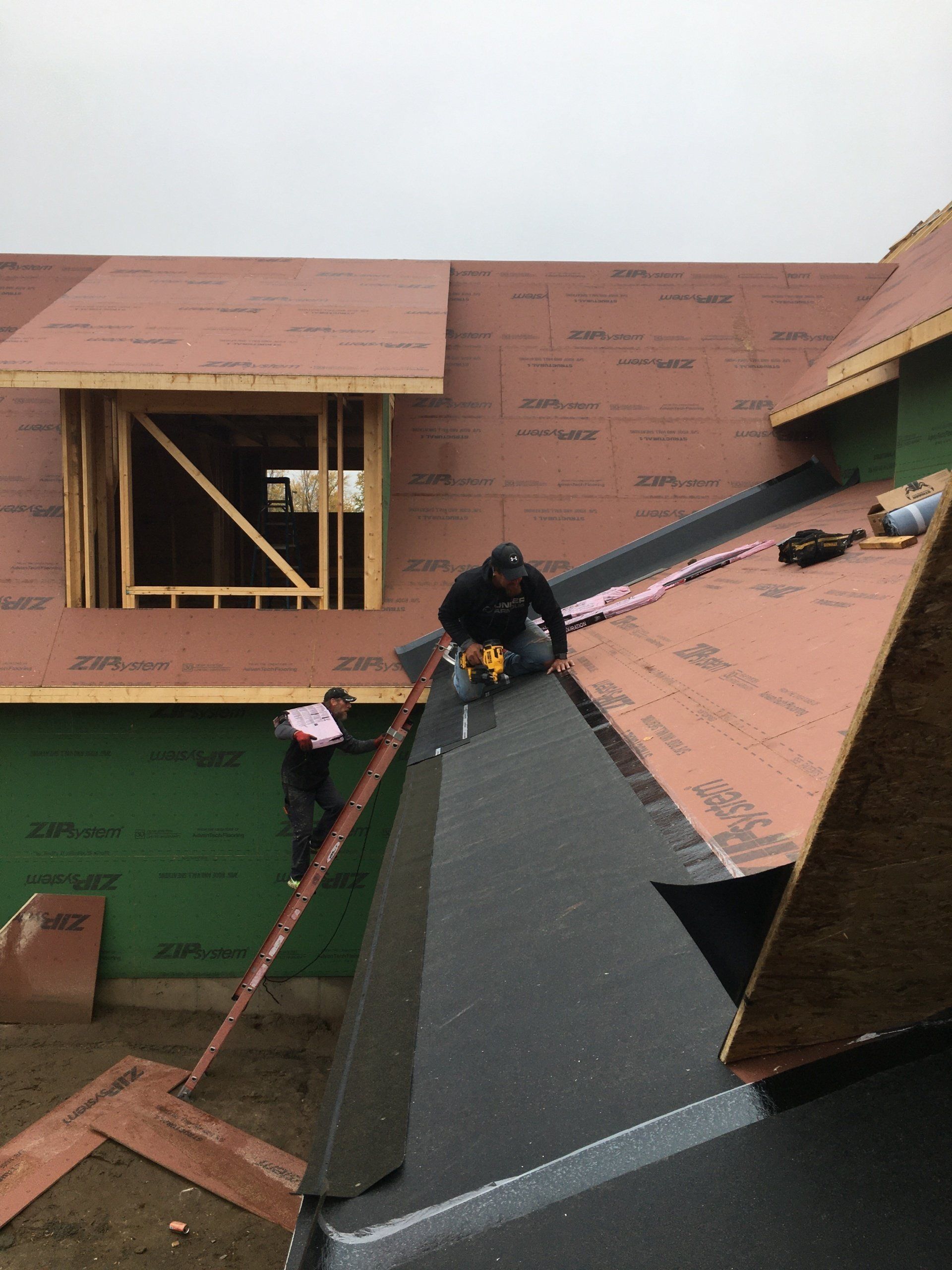 A man is working on the roof of a house under construction