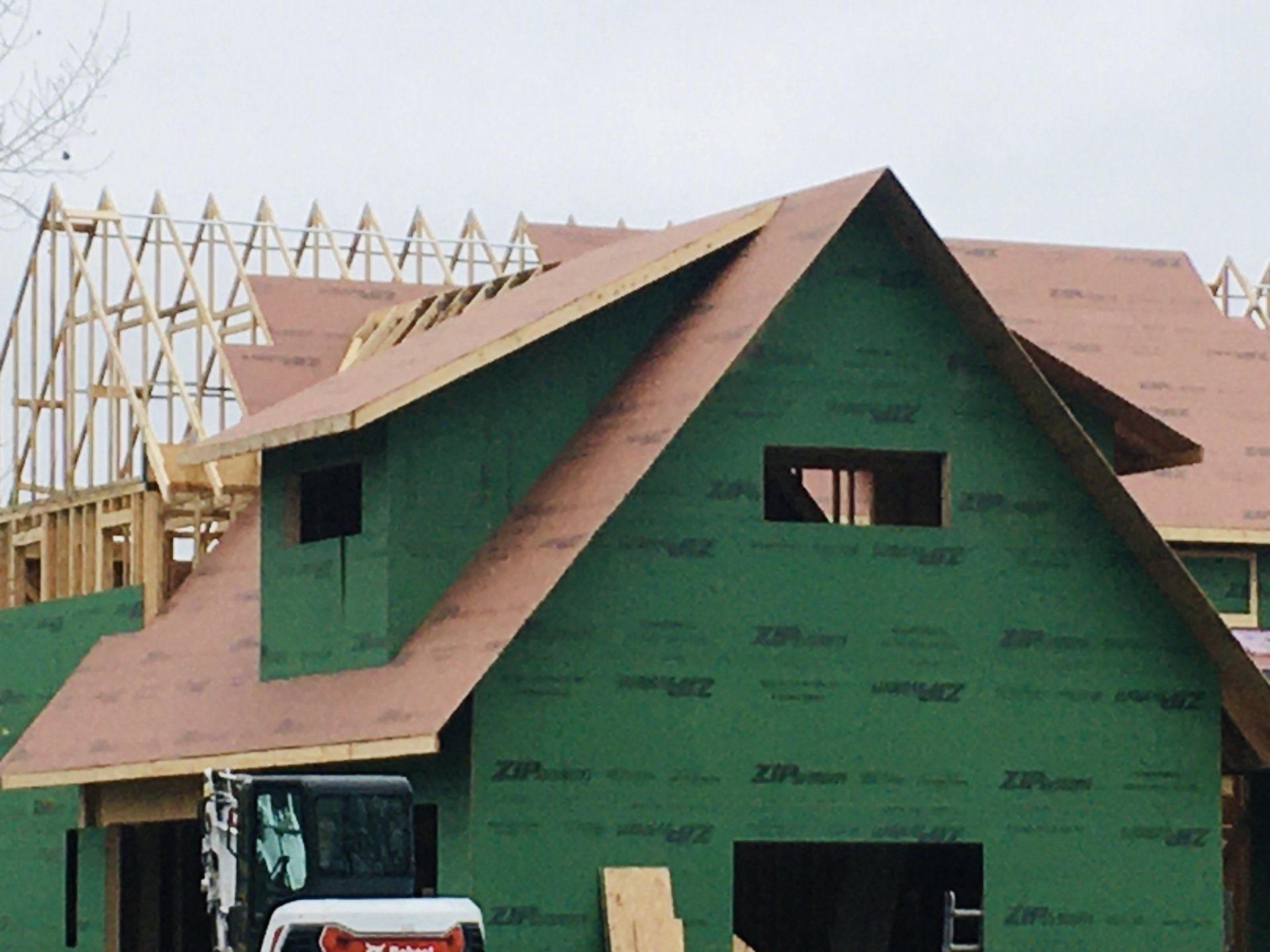 A bobcat is parked in front of a house under construction