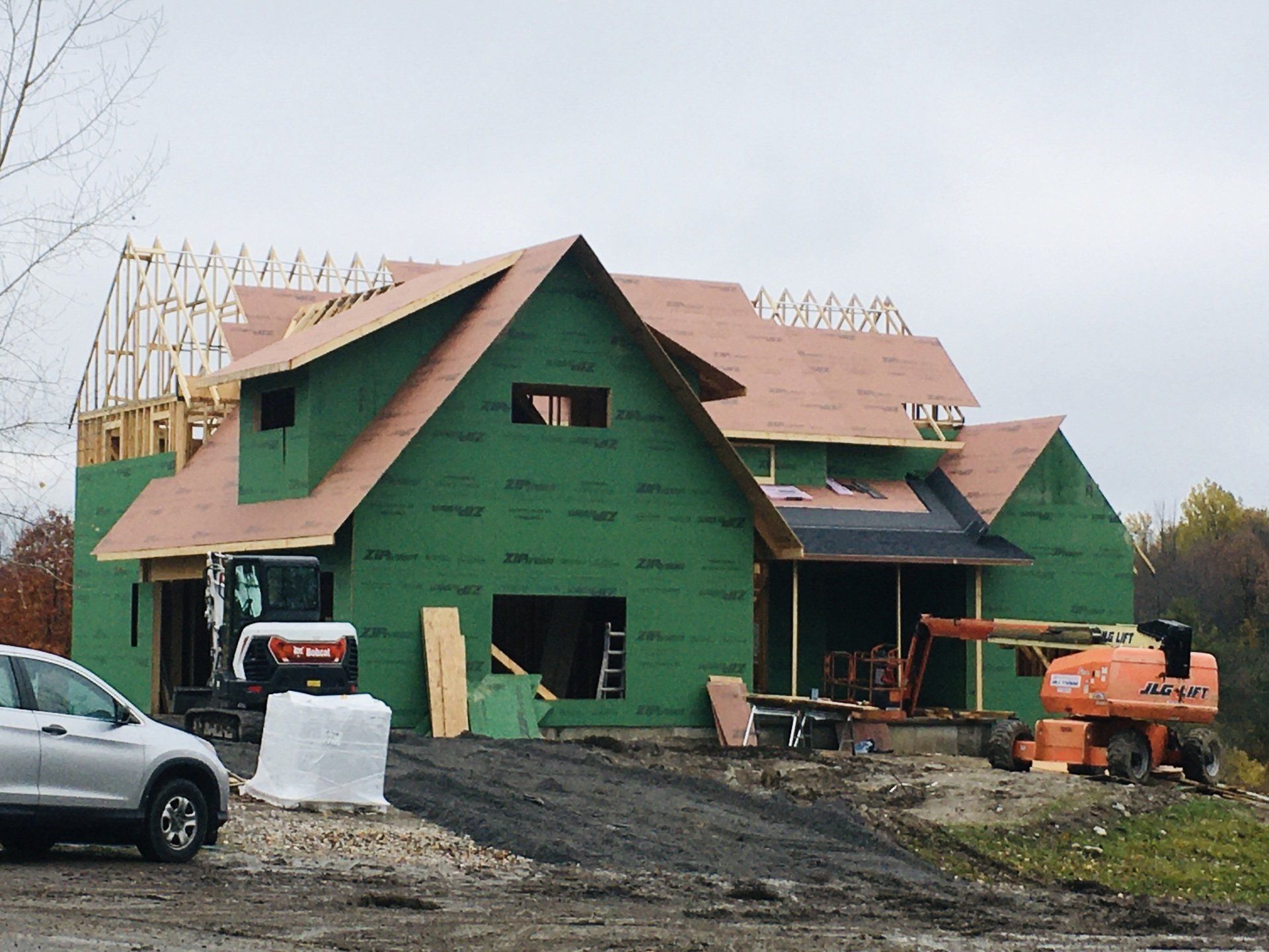 A car is parked in front of a house under construction.