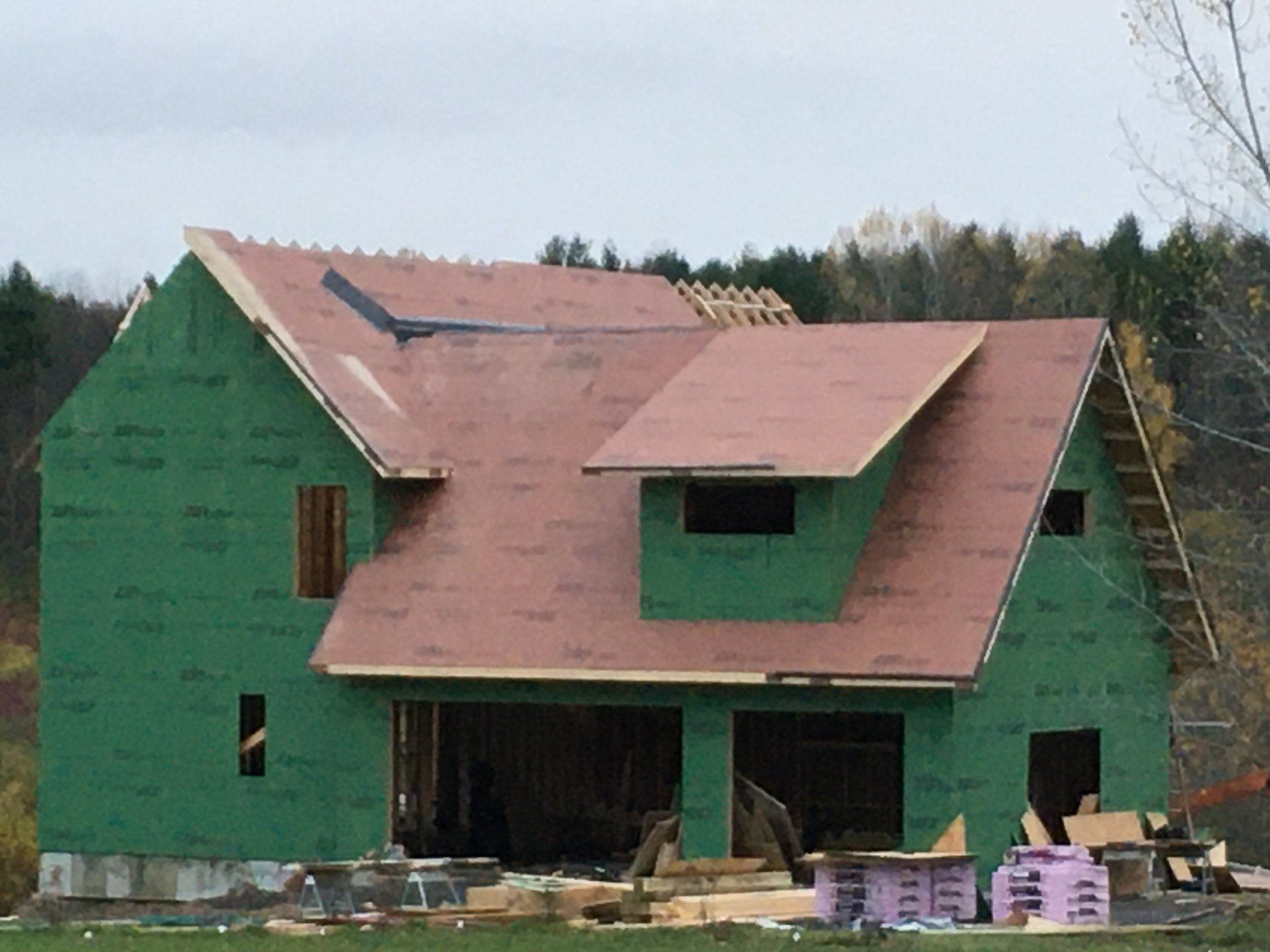 A green house with a red roof is under construction