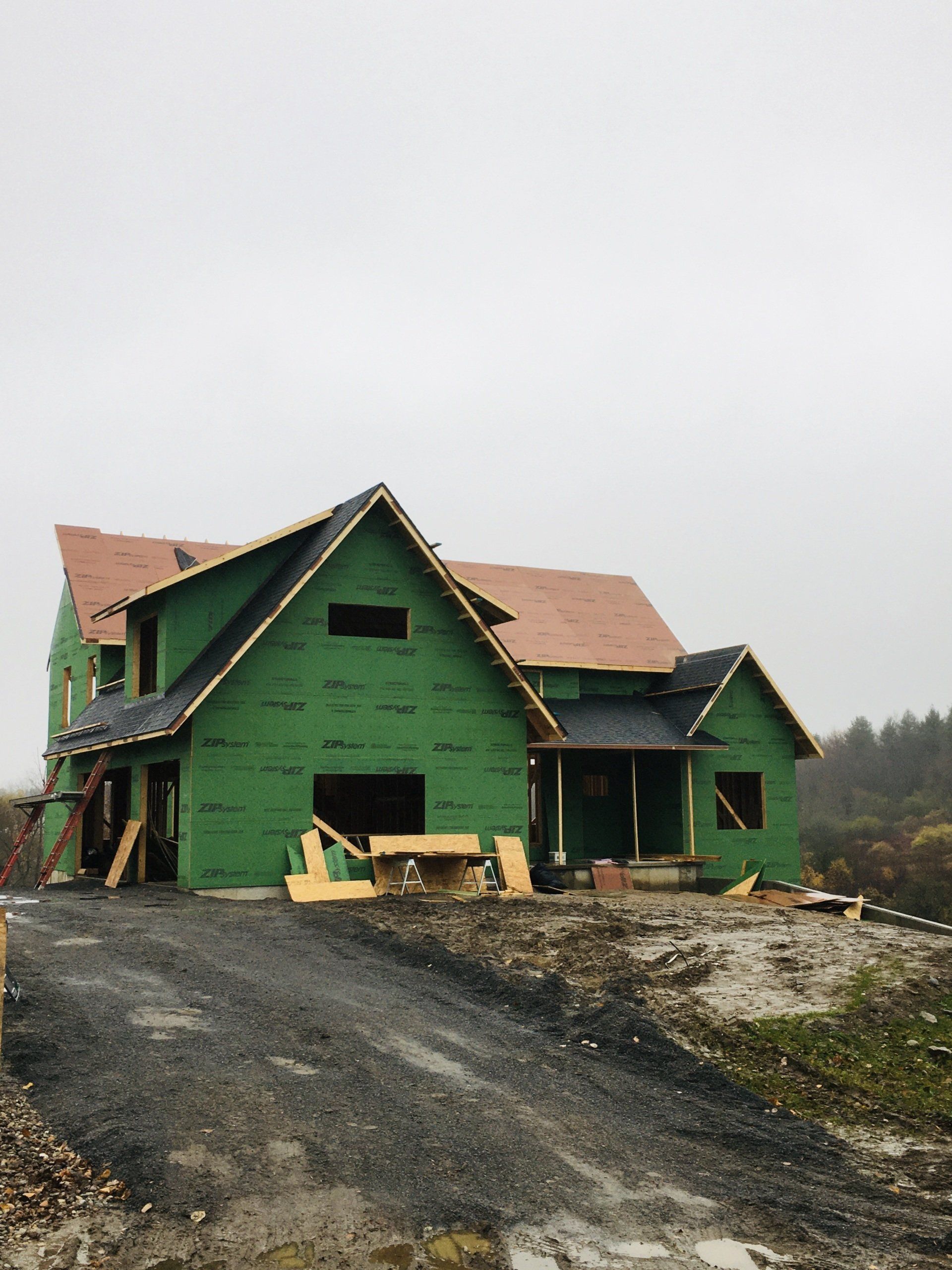A house is being built with green siding and a roof.