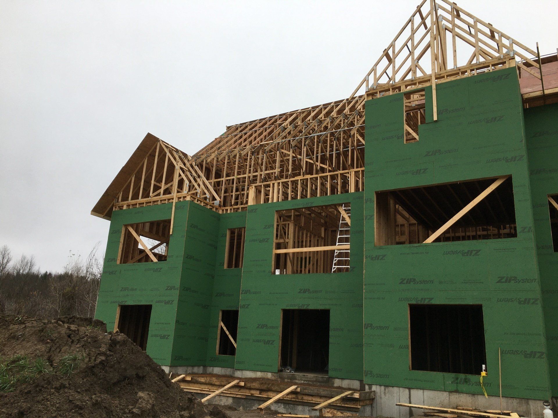 A large house is being built with green walls and a wooden roof.
