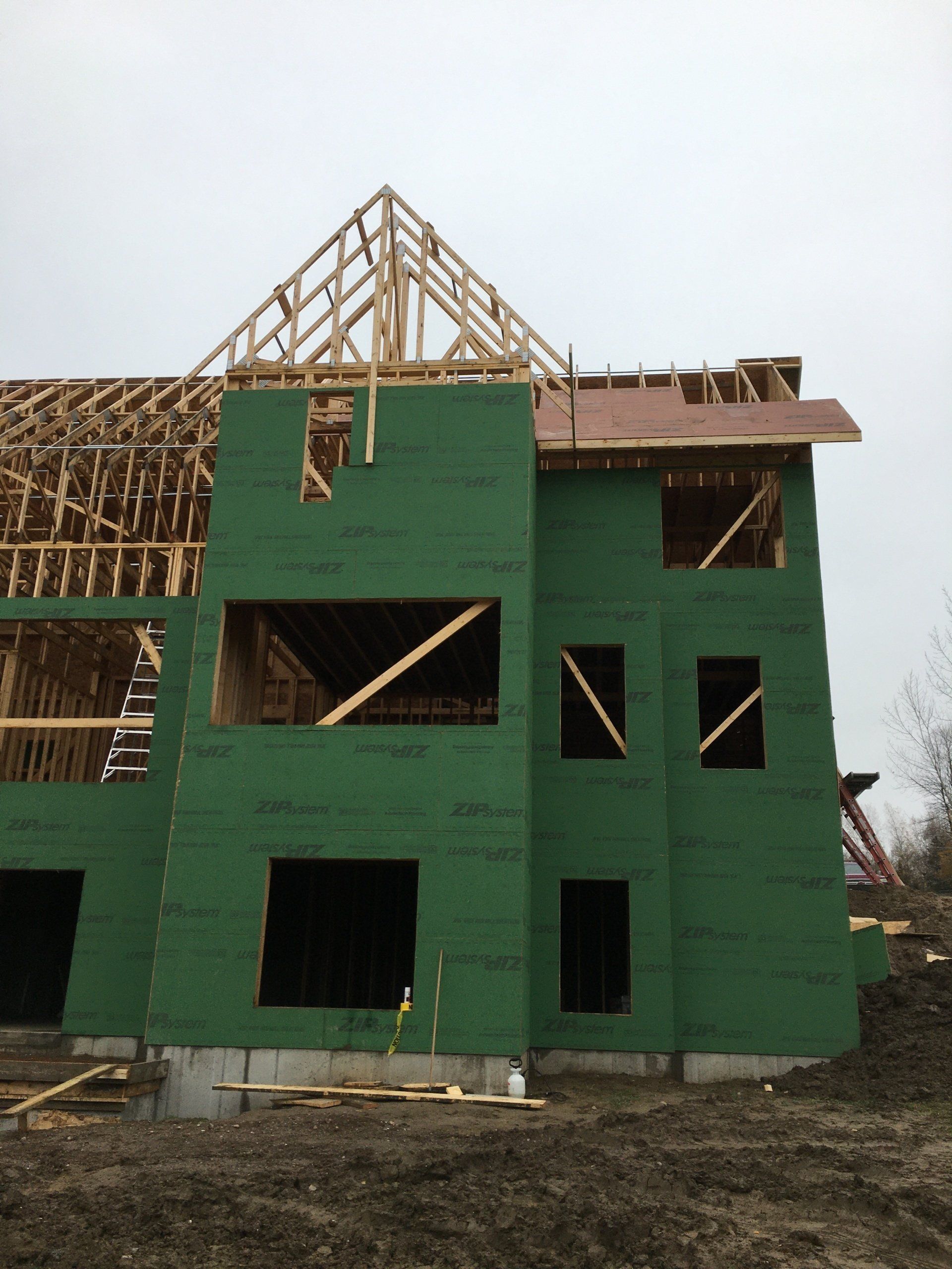 A building under construction with green walls and a wooden roof