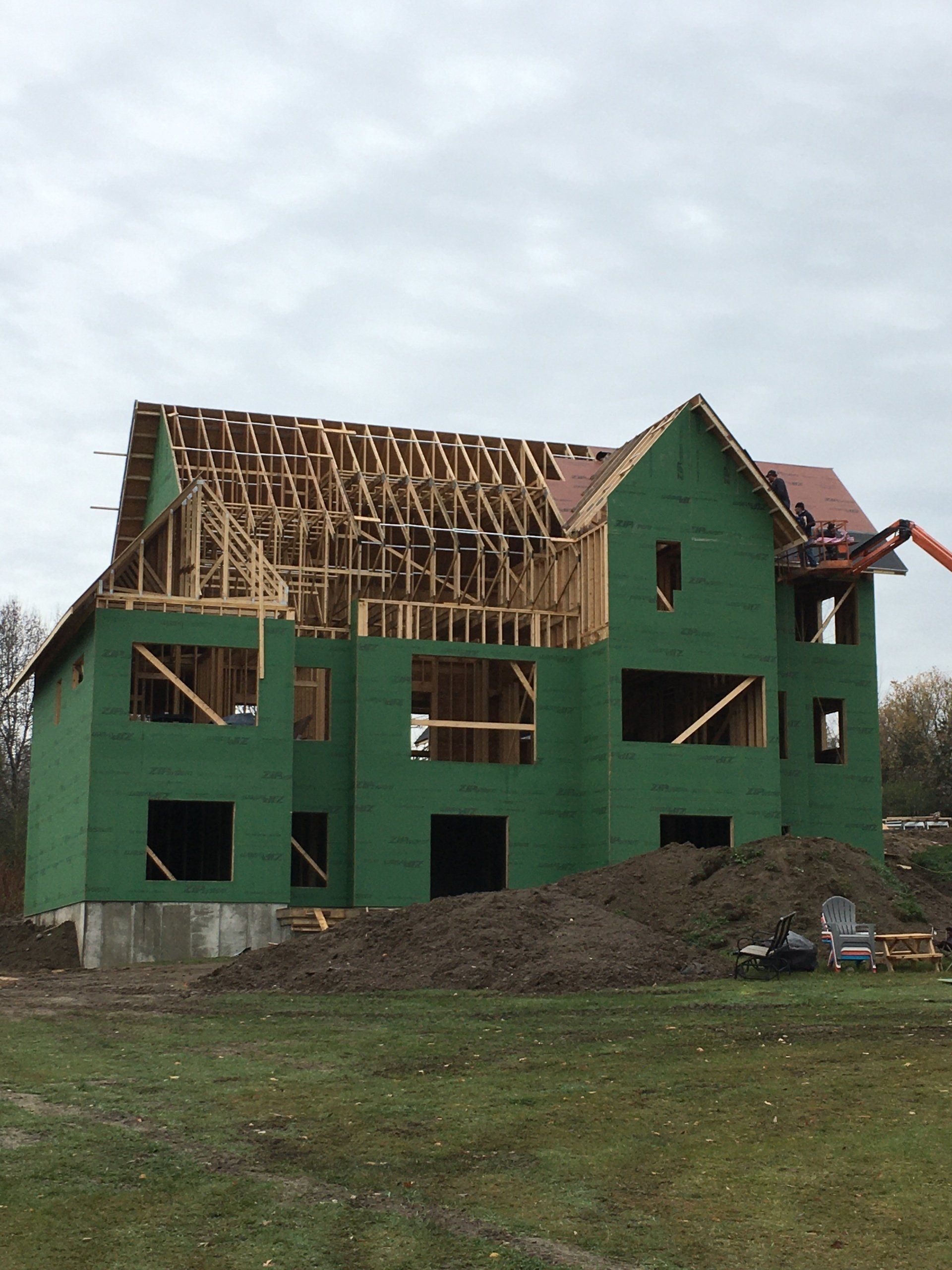 A house is being built with green walls and a red roof