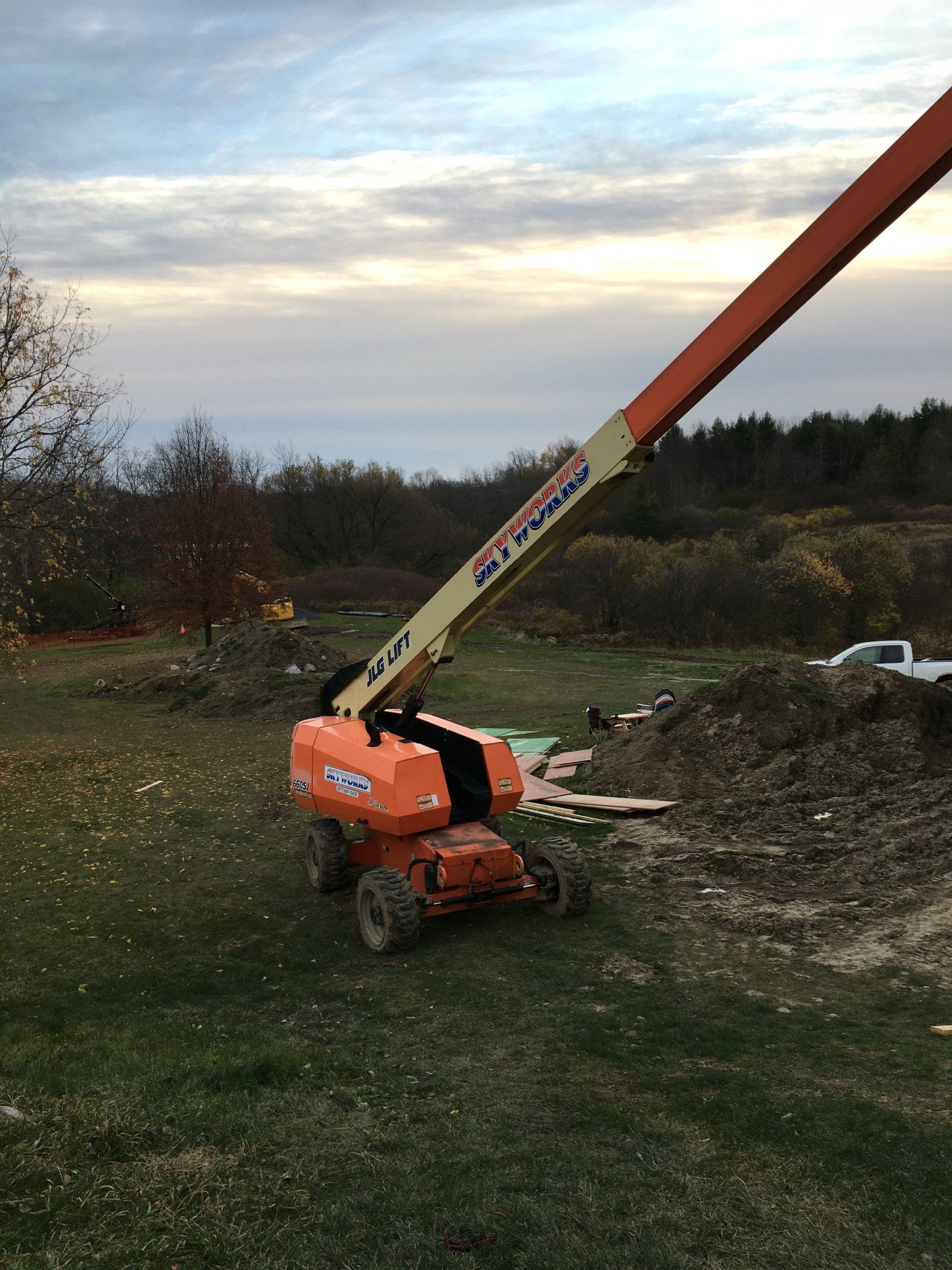 A large orange crane is sitting in the middle of a grassy field.