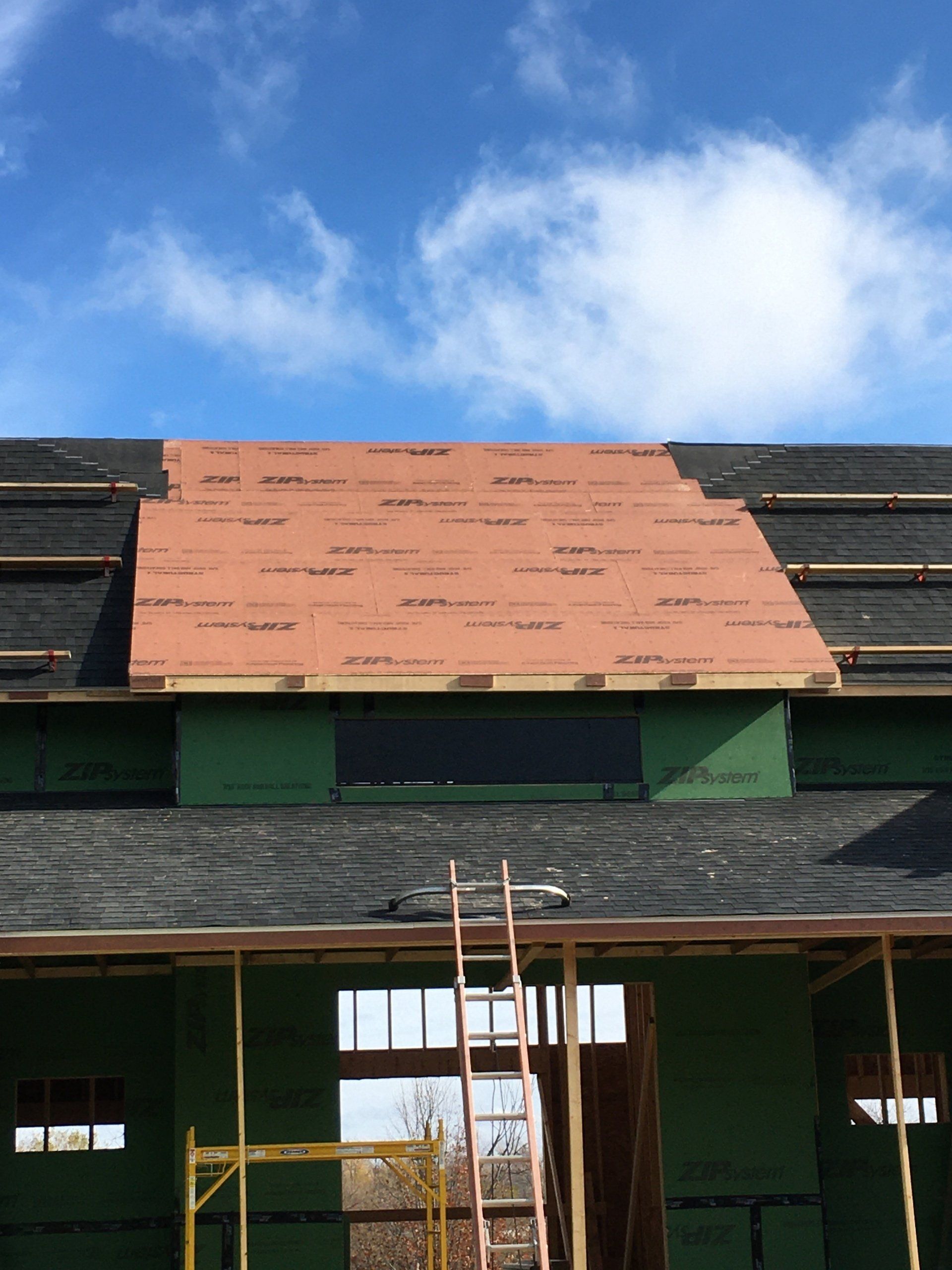 A roof is being installed on a house under construction