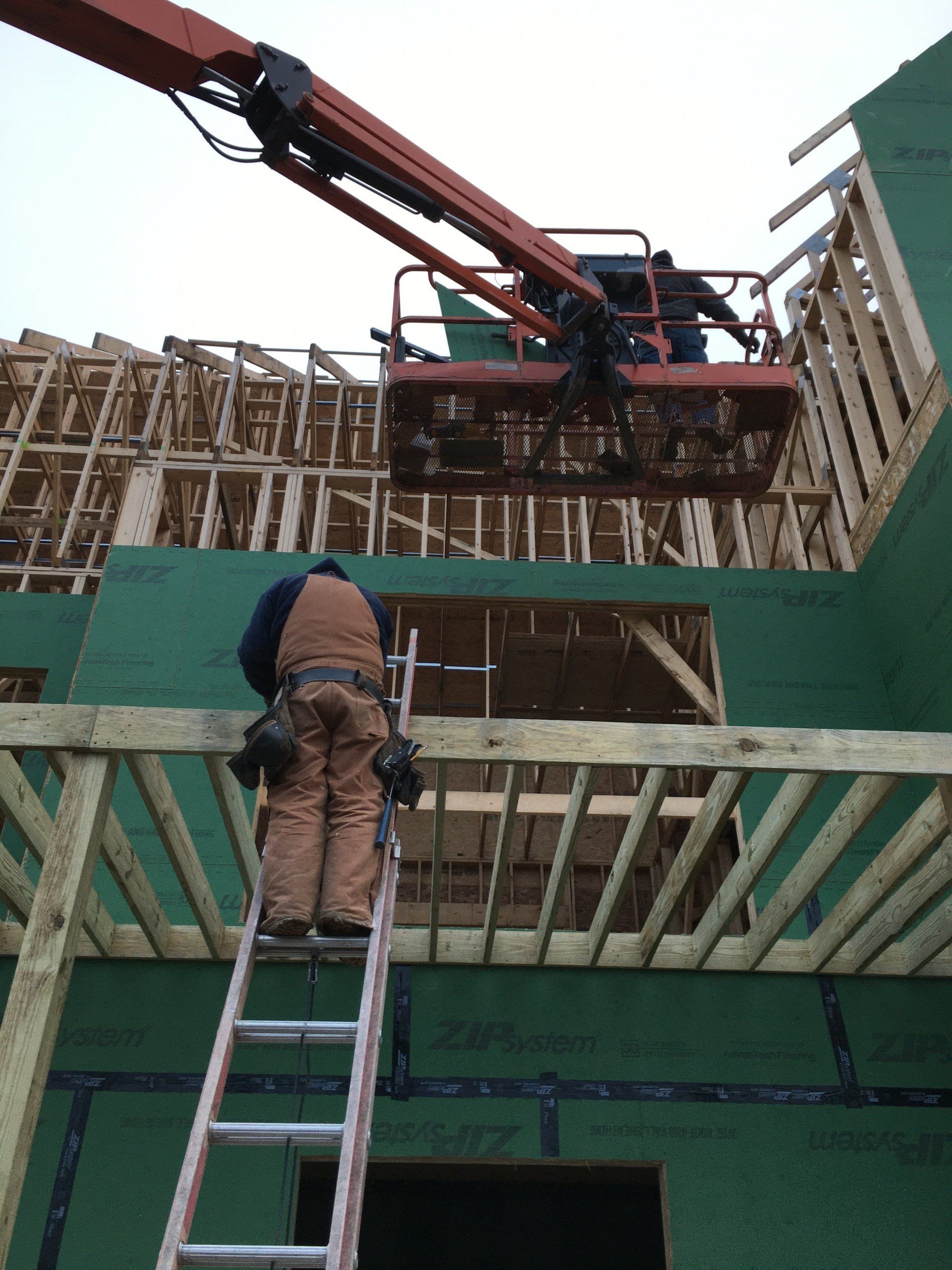 A man standing on a ladder in front of a building under construction