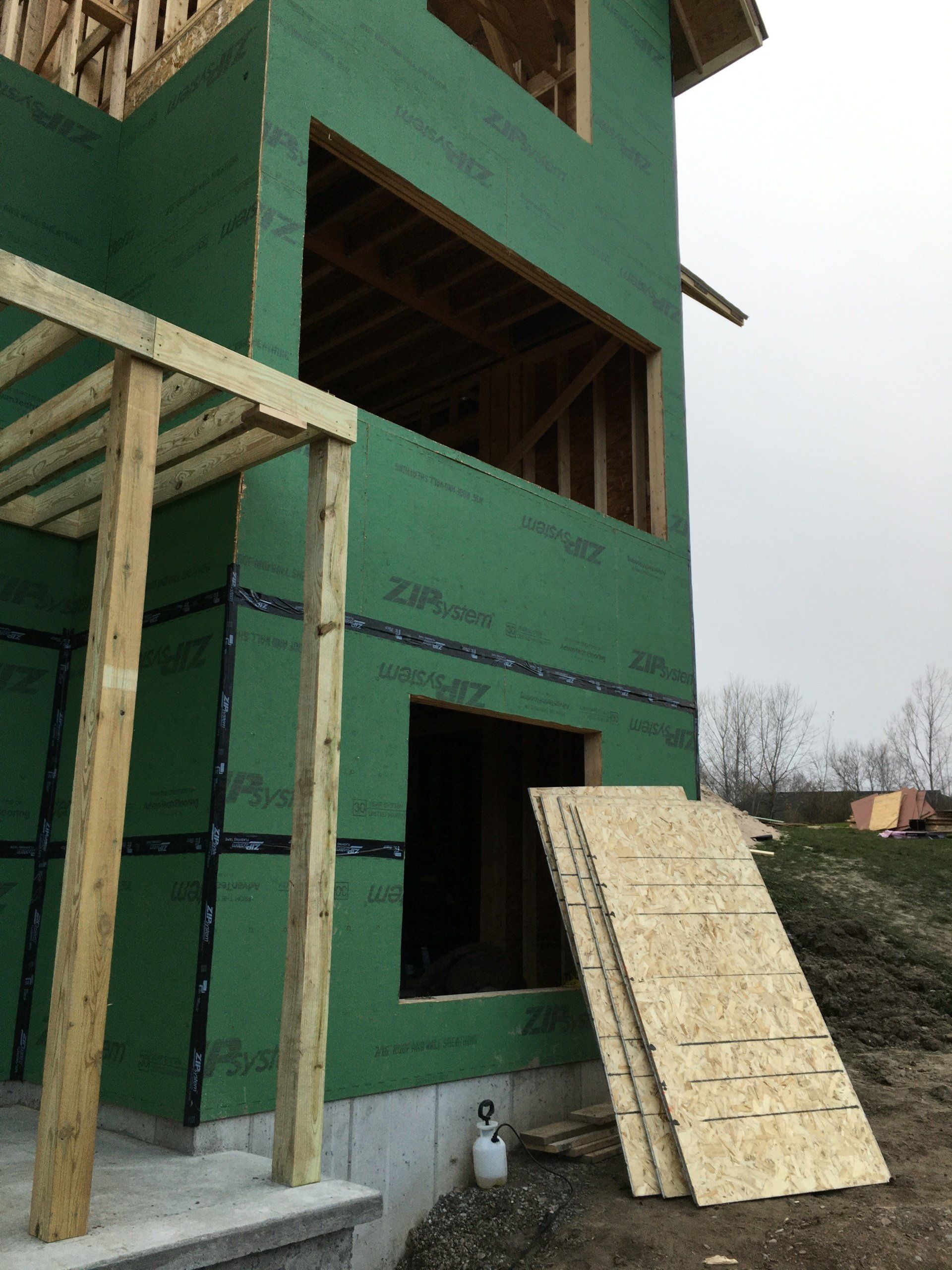 A house under construction with green walls and wooden beams