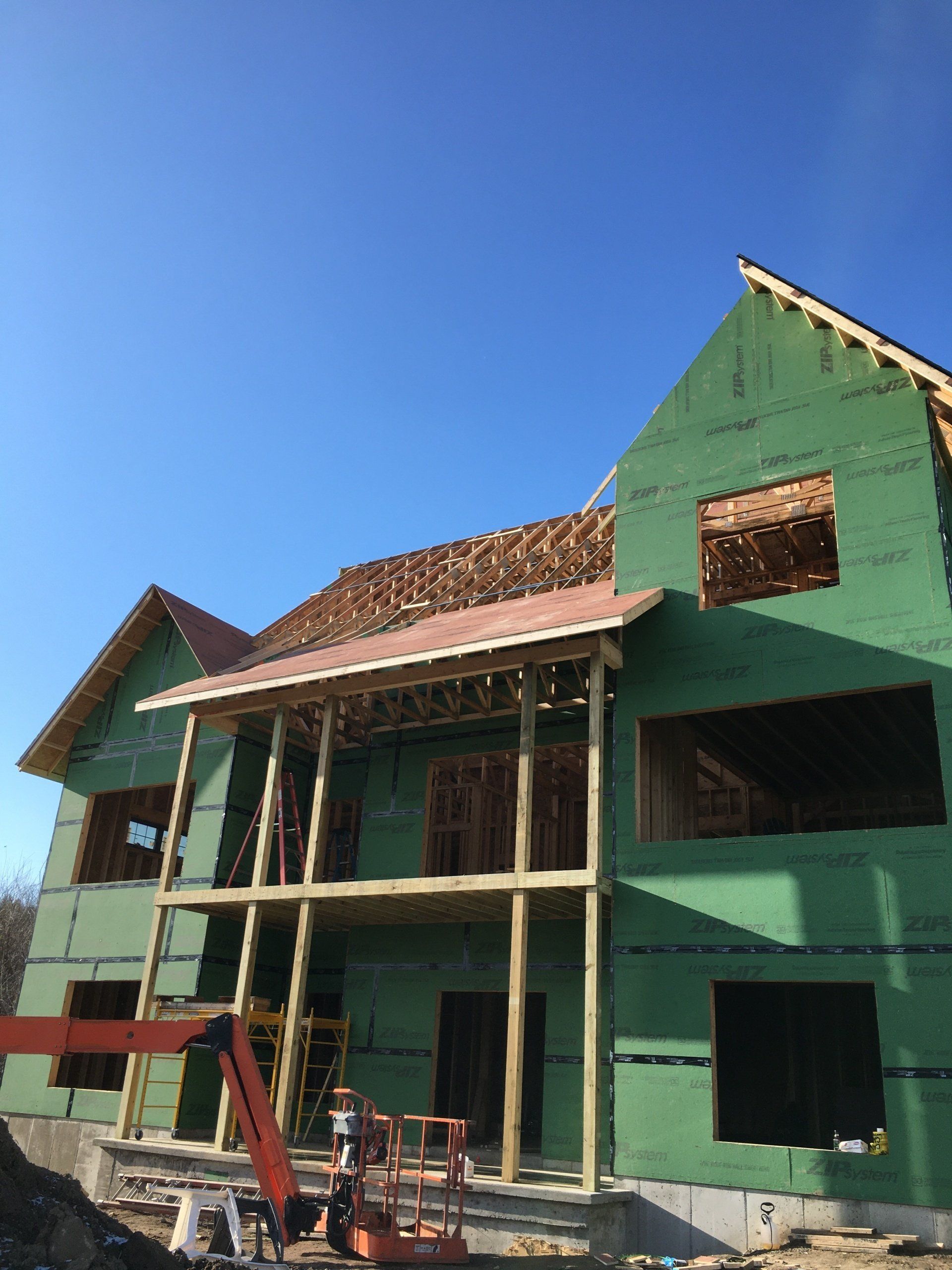 A large house is being built with green walls and a red roof.