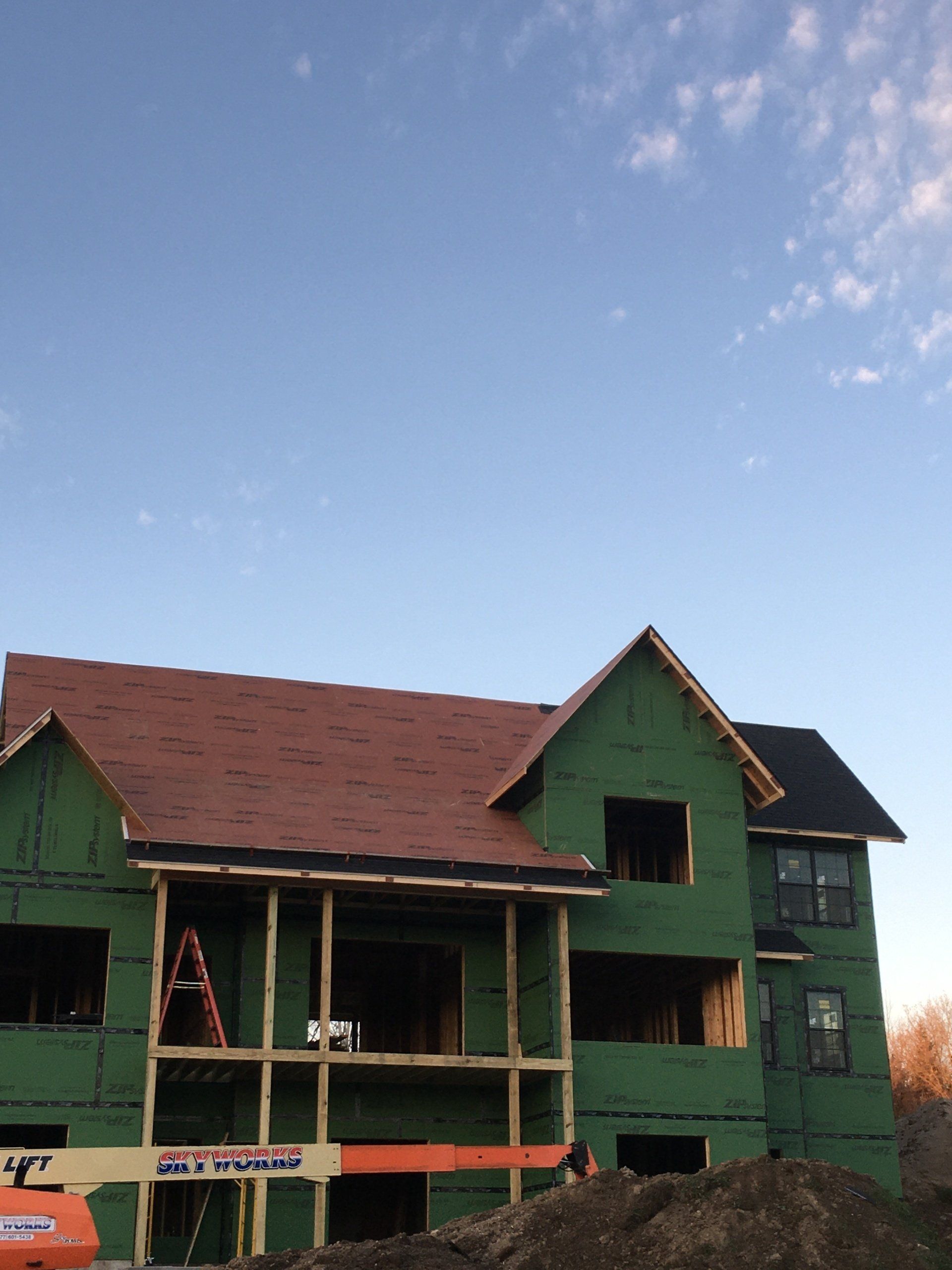 A house under construction with a jlg lift in front of it