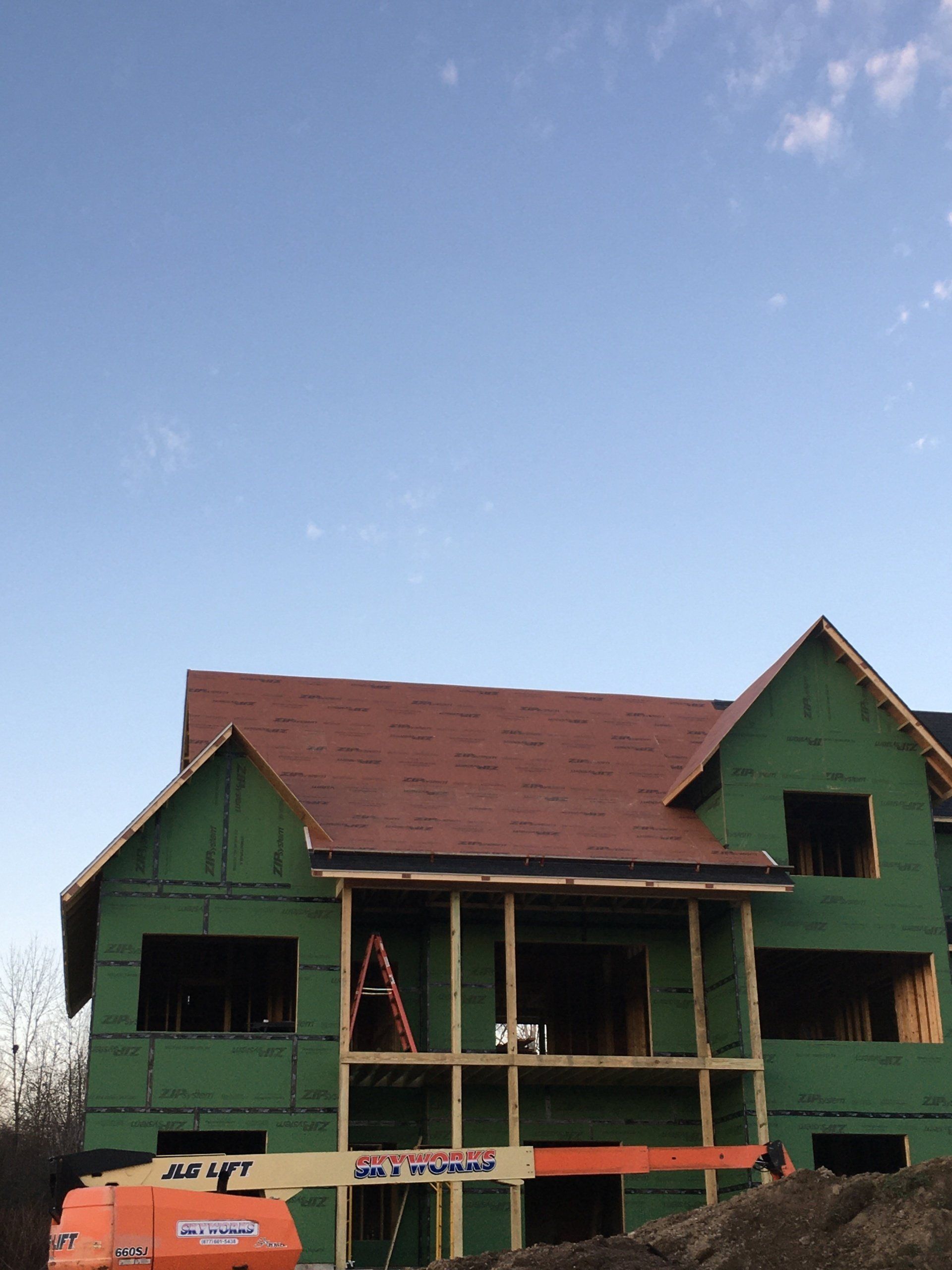 A large house is being built with a red roof.