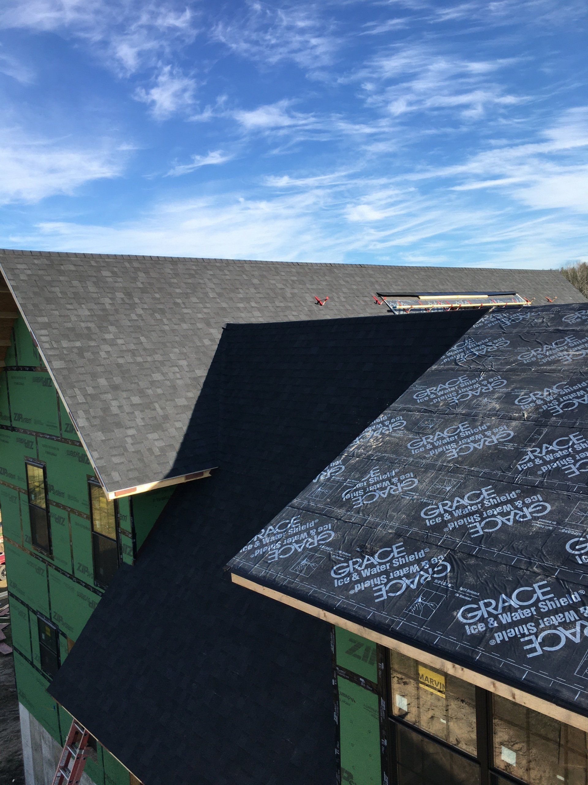 A roof is being installed on a house under construction.