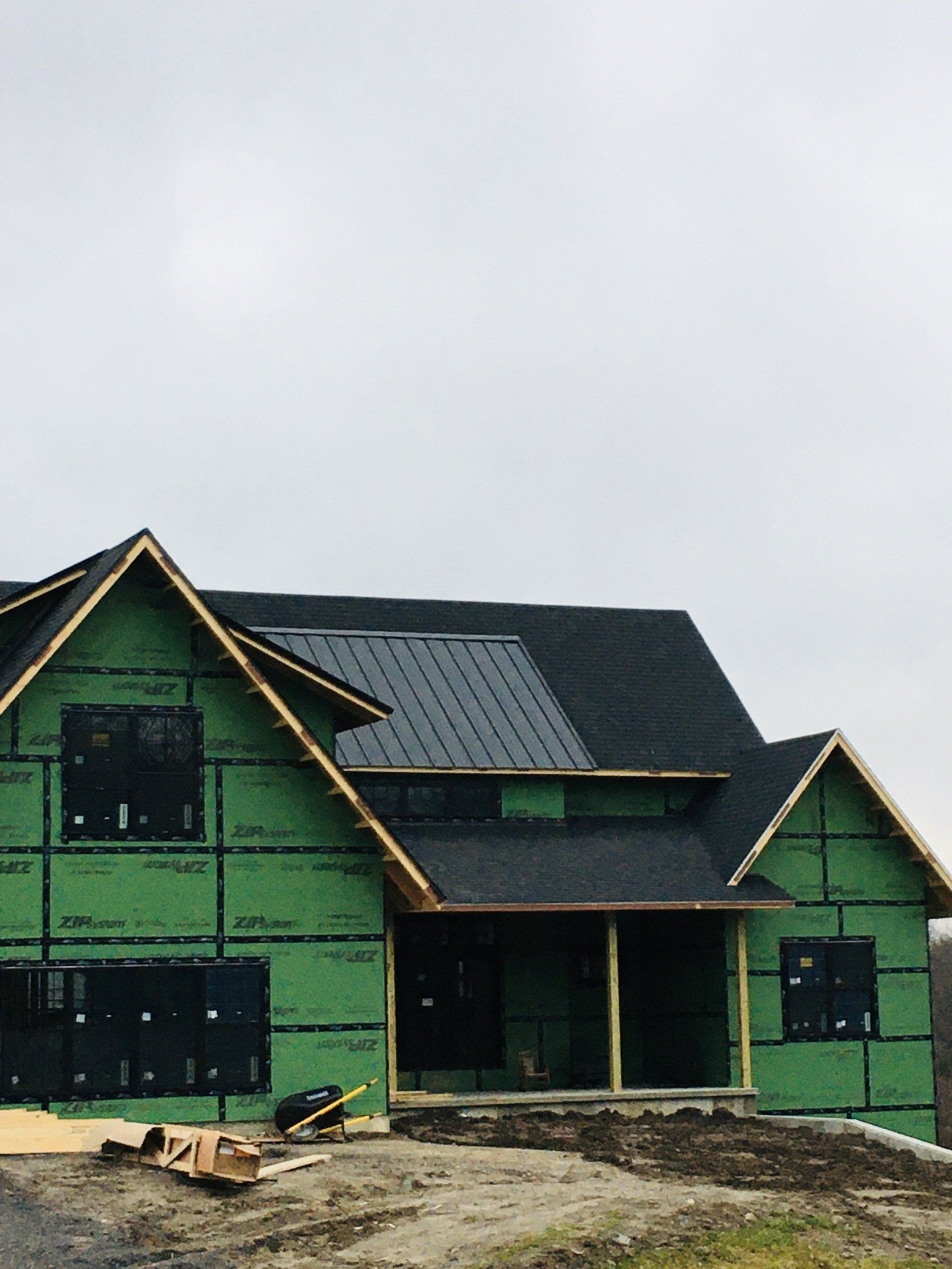A house is being built with green siding and a black roof