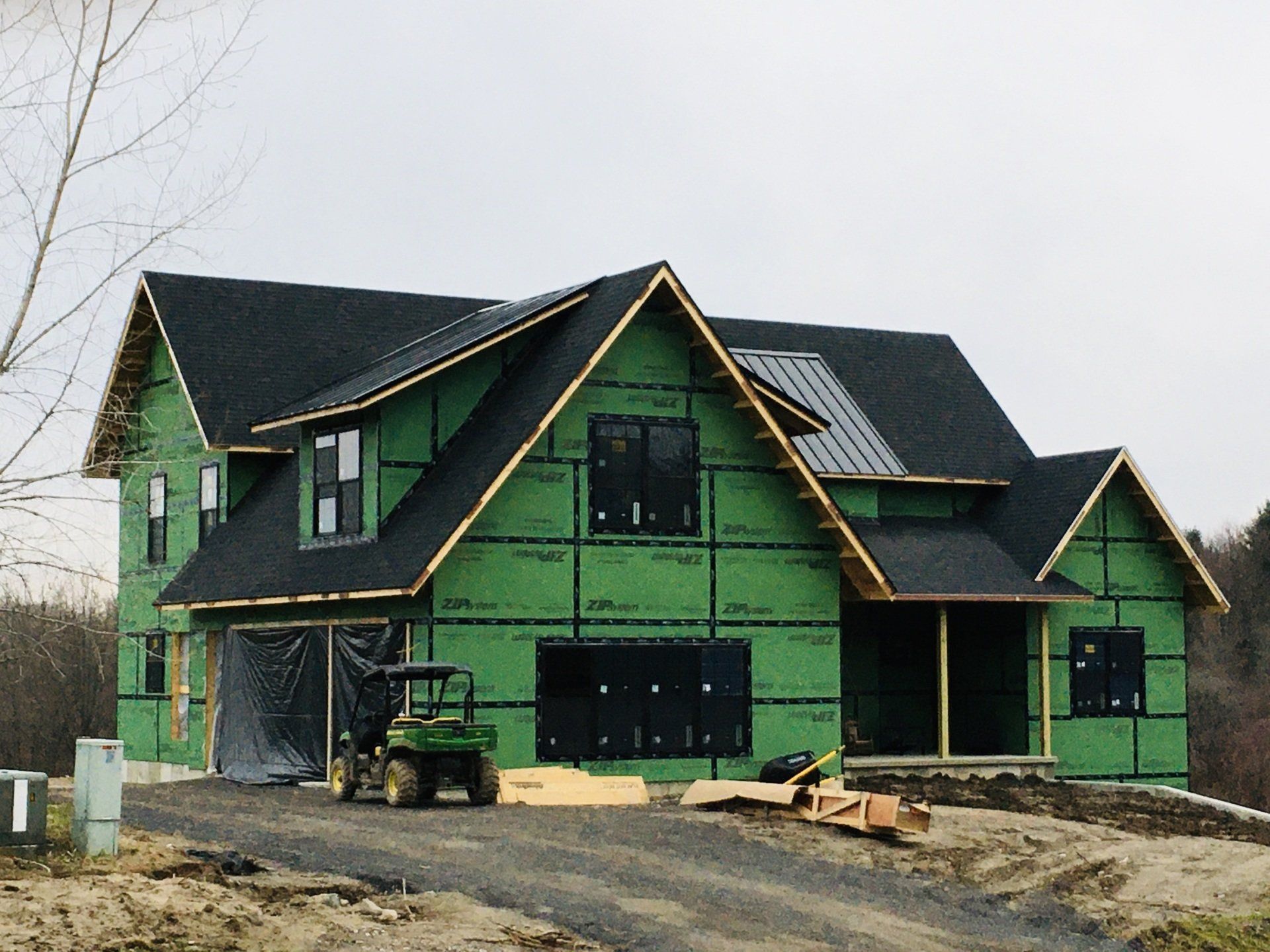 A house under construction with a tractor parked in front of it