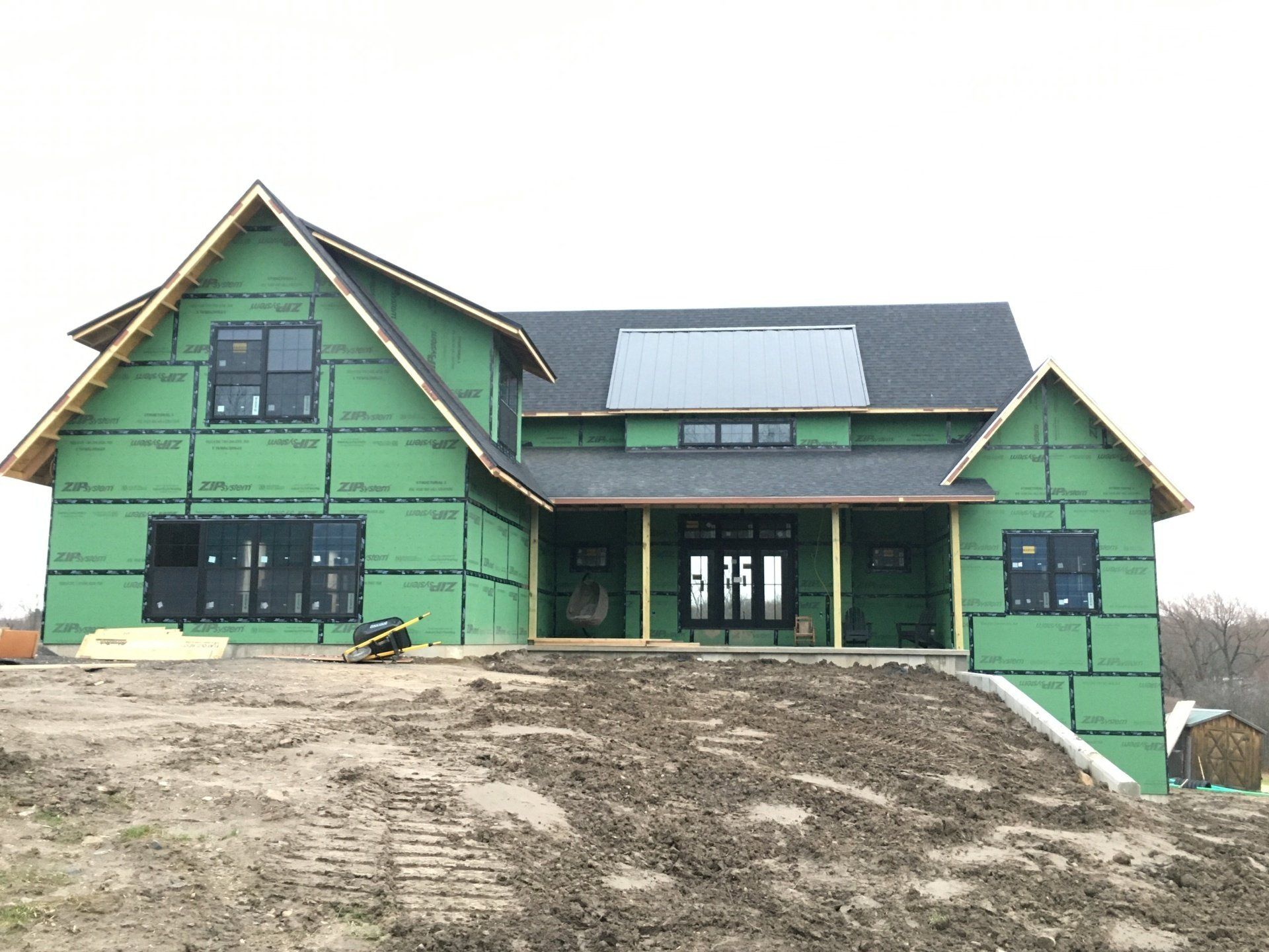 A house is being built with green insulation and a black roof.