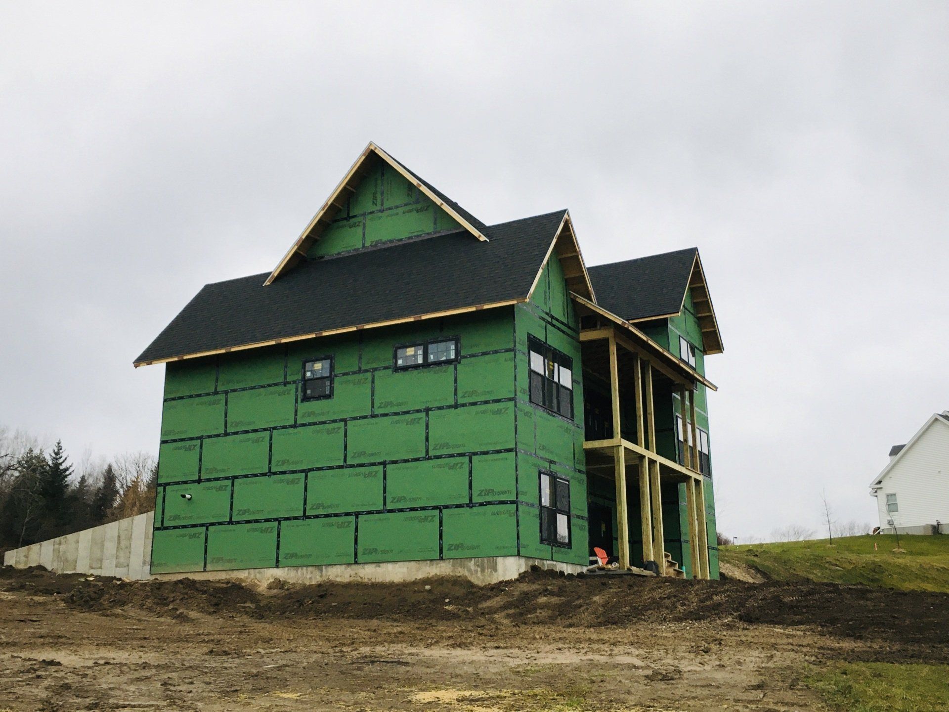 A house is being built with green siding and a black roof.