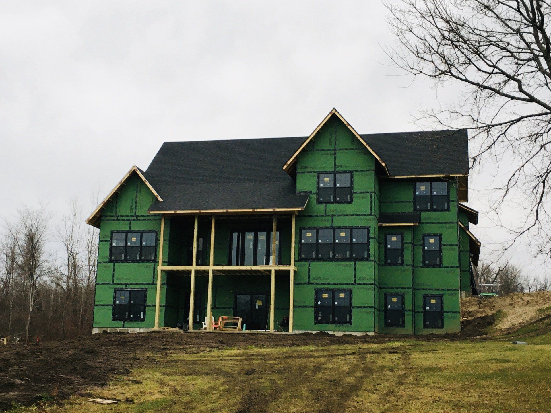 A large house is being built in the middle of a grassy field.