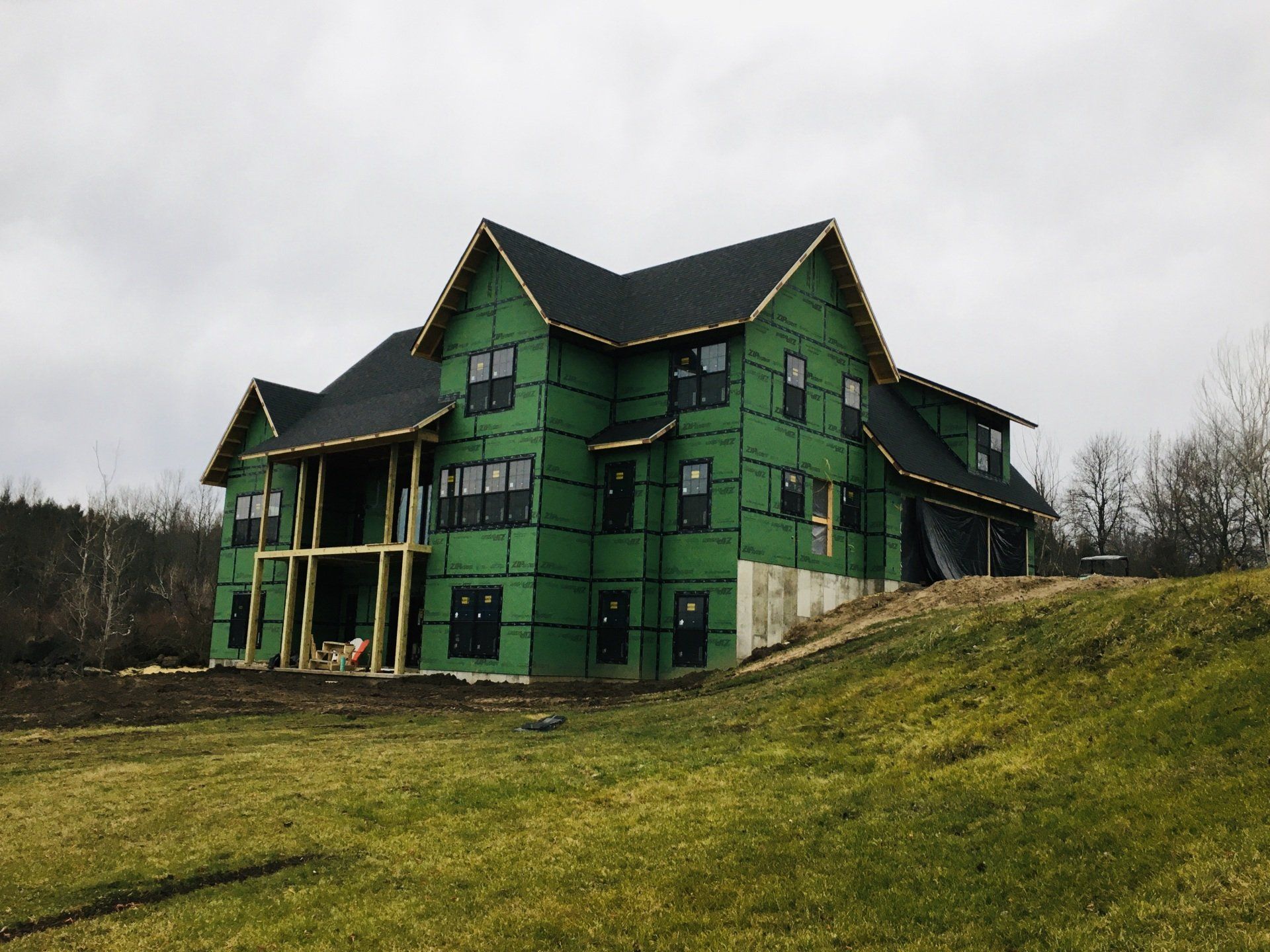 A large green house is being built on top of a grassy hill.