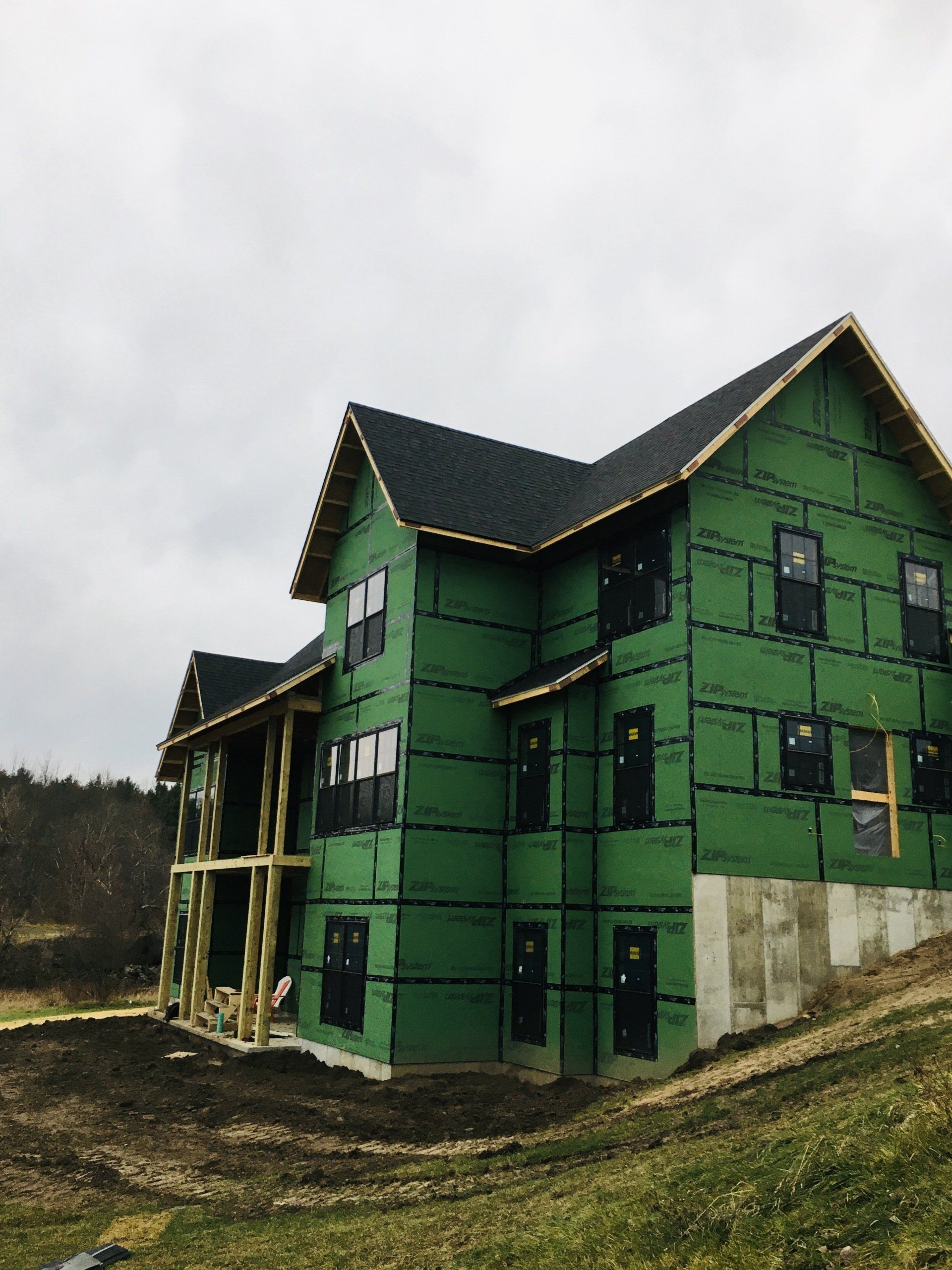 A large green house with a black roof is under construction.